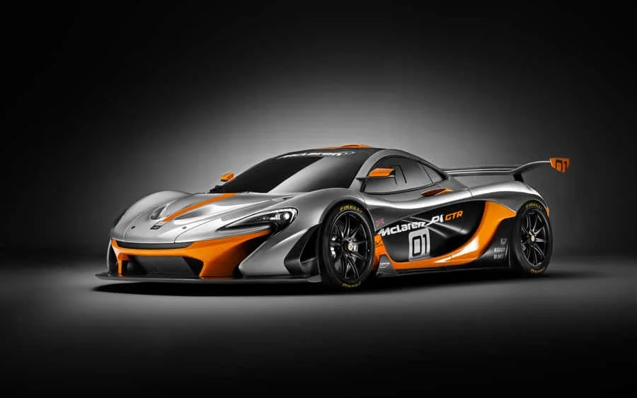 A silver and orange McLaren racing car with aerodynamic design and a large rear wing displayed on a dark background.