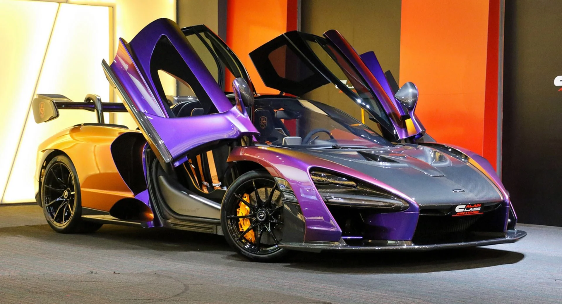 A luxury sports car with butterfly doors open, featuring a purple and black color scheme, on display indoors.