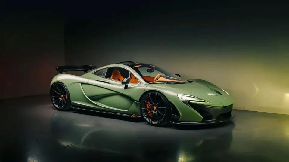 A lime green sports car with black wheels and orange accents inside a dark showroom.
