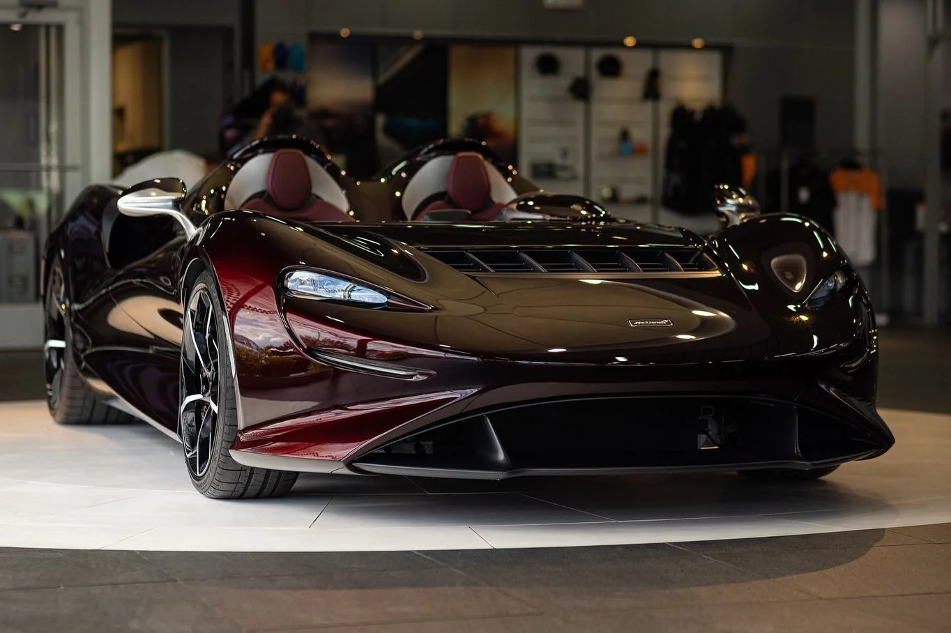 A sleek, black luxury sports car with a convertible top on display indoors, with a modern showroom background.