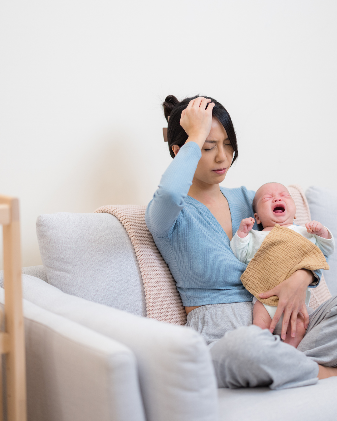 Mother with newborn frustrated with crying baby due to sensory overwhelm.