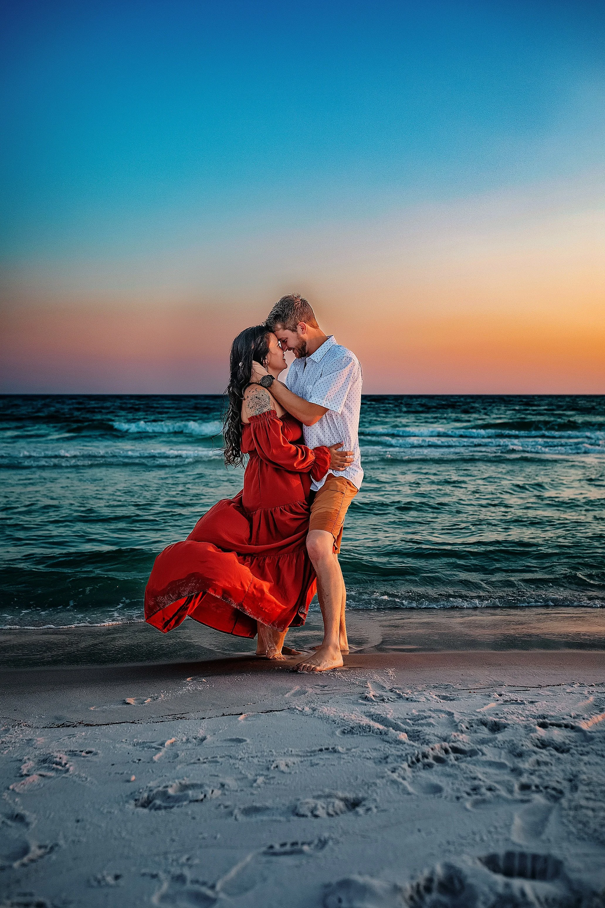 a couple embracing during their maternity beach session at sunset on the Destin beach