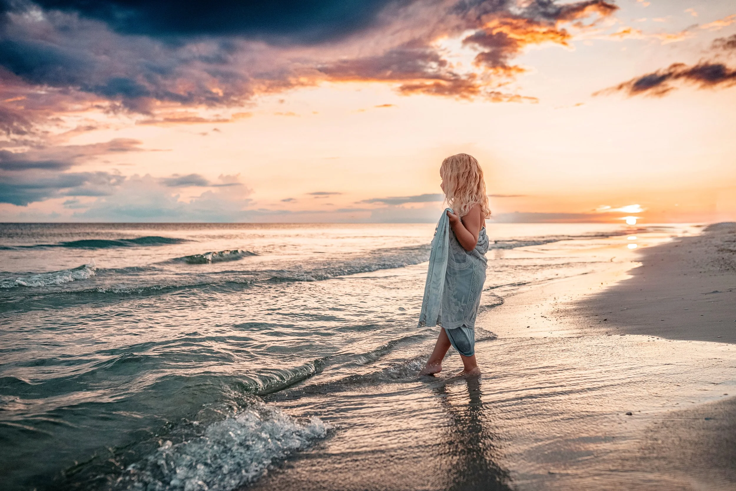 Young child standing at the shoreline during a golden sunset beach session with a 30A family beach photographer