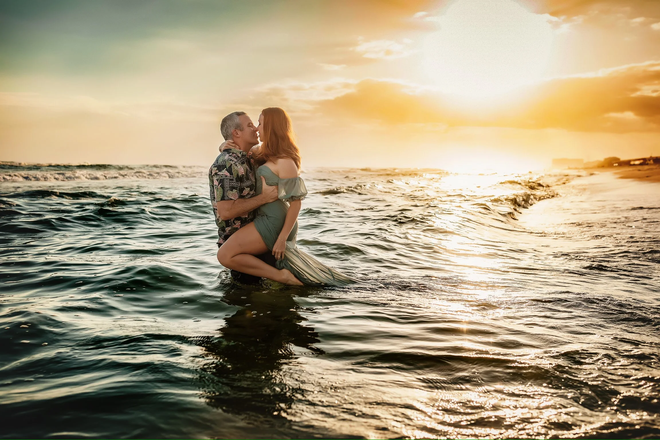 A couple embracing in the water off the Miramar beach during their sunset session