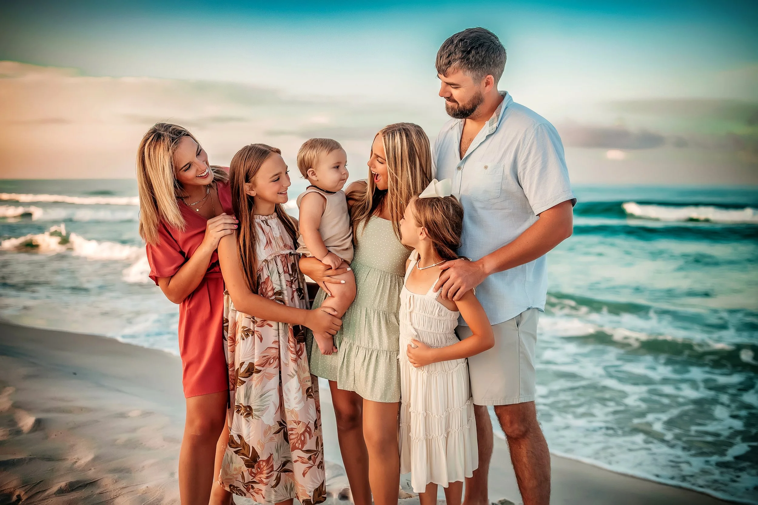 Extended family standing together on the shoreline during a sunset beach photography session along 30A.