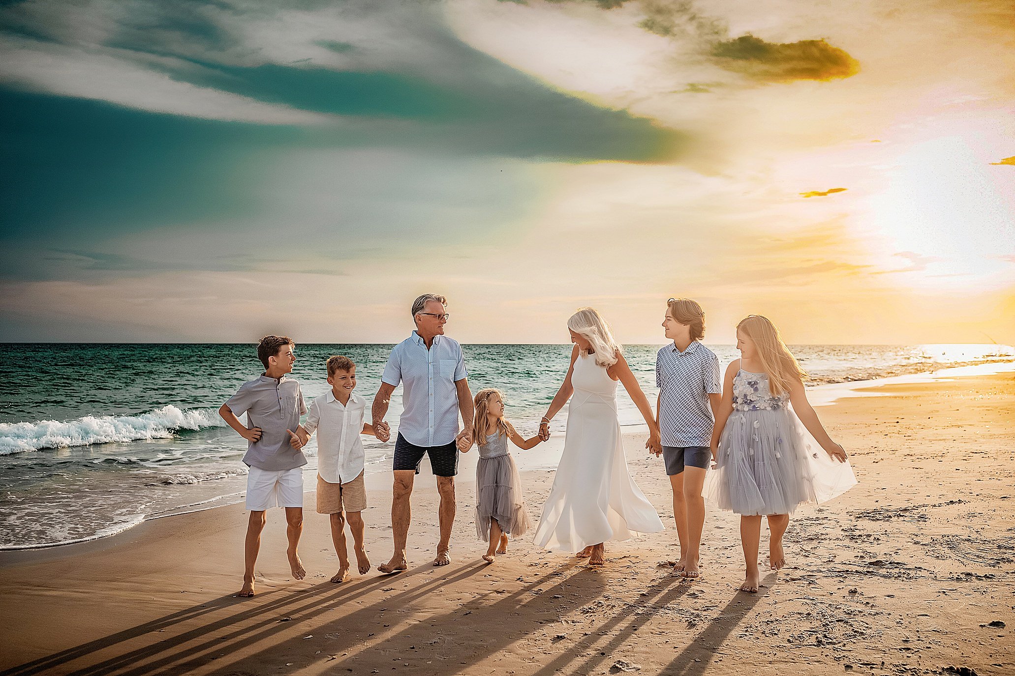 Extended family wearing coordinated white linen and tan outfits for a luxury beach portrait session on 30A.