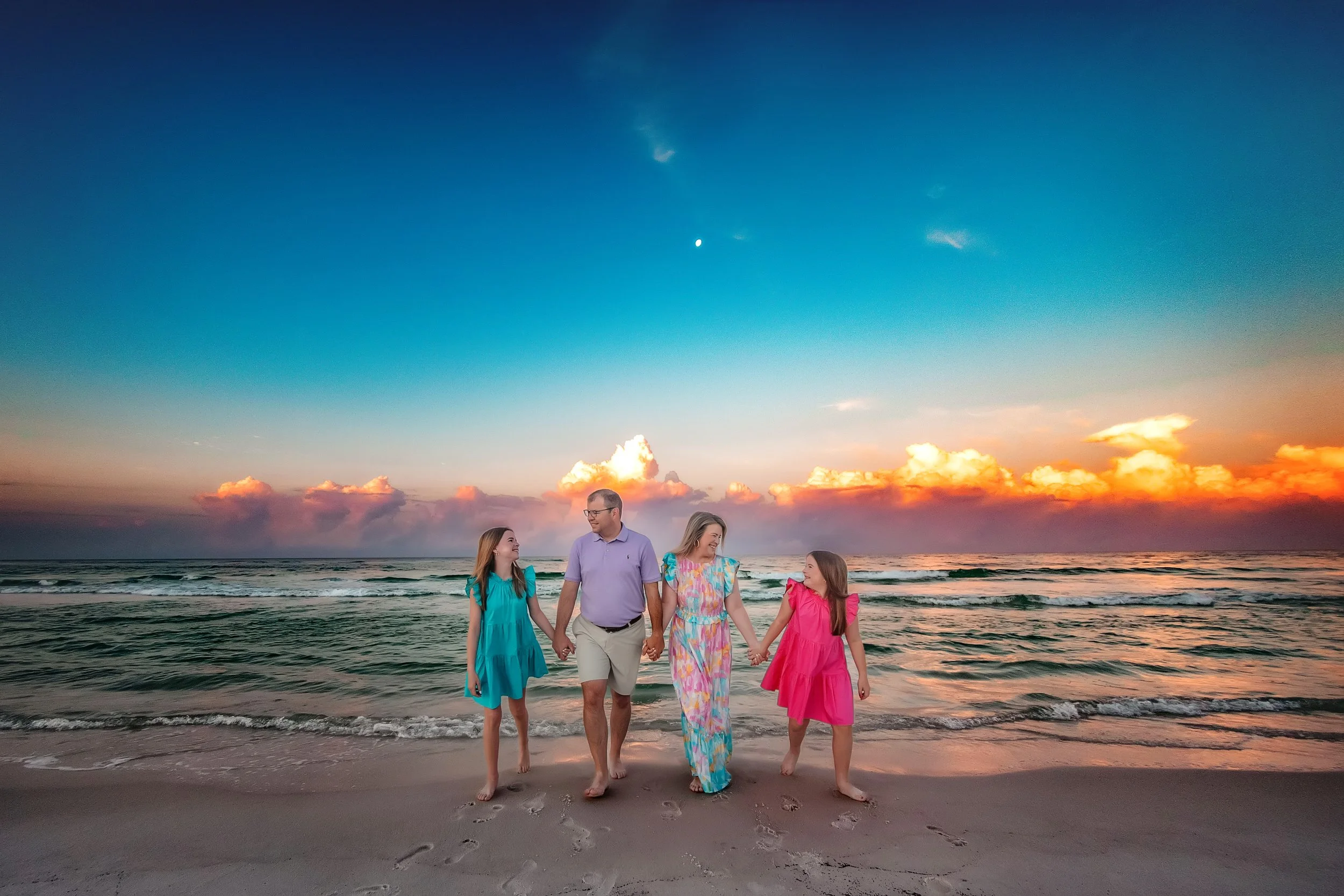 Family walking on the 30A beaches at sunrise against beautiful cloud coverage