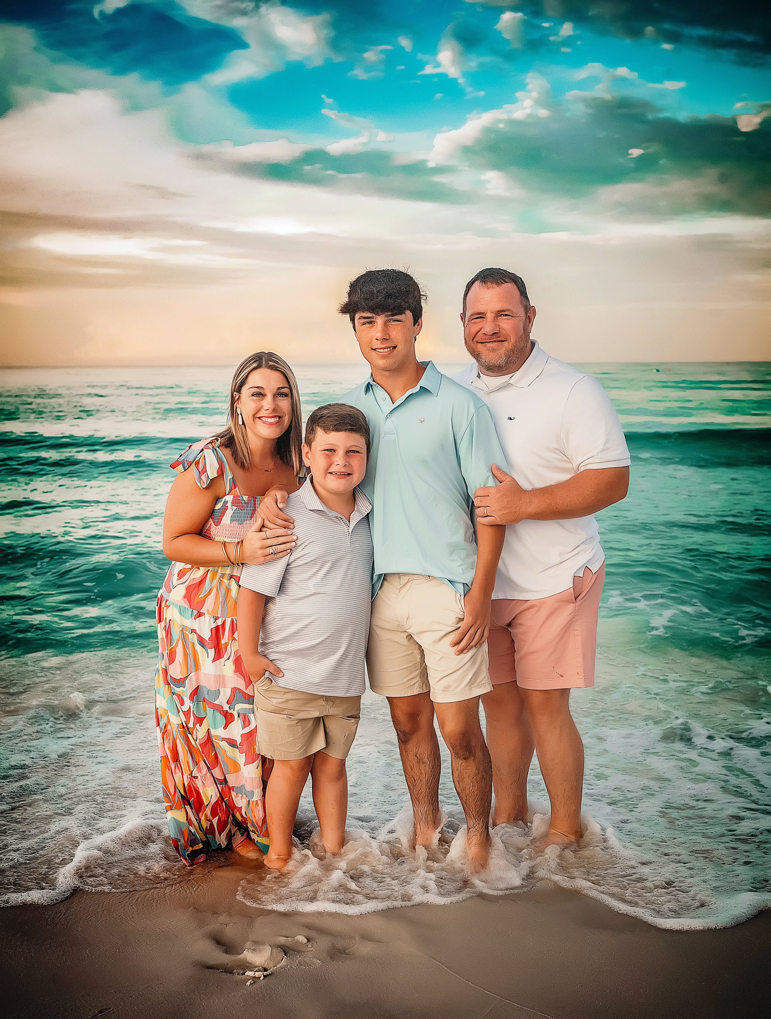 Family of four standing in the shallow water at sunset during a beach session in Panama City Beach, photographed by a professional Panama City Beach family photographer.