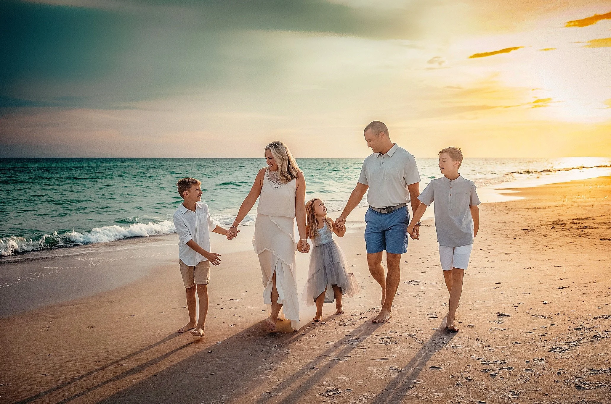 Family of five walking hand in hand during their sunset beach session in Destin Florida