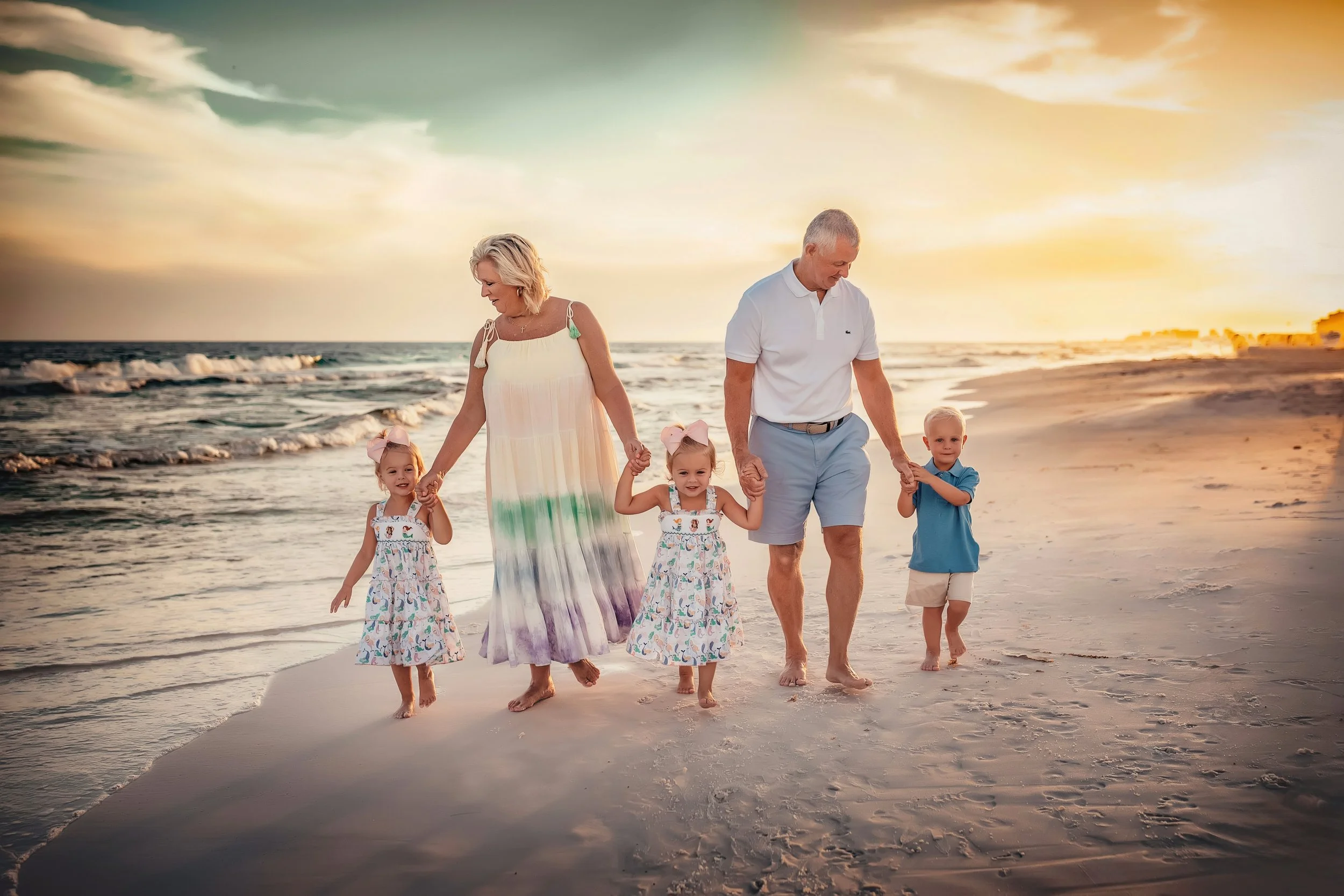 Grandparents holding their grandchildren hands as they walk the beach during a golden sunset during they 30A Sunset Beach Session