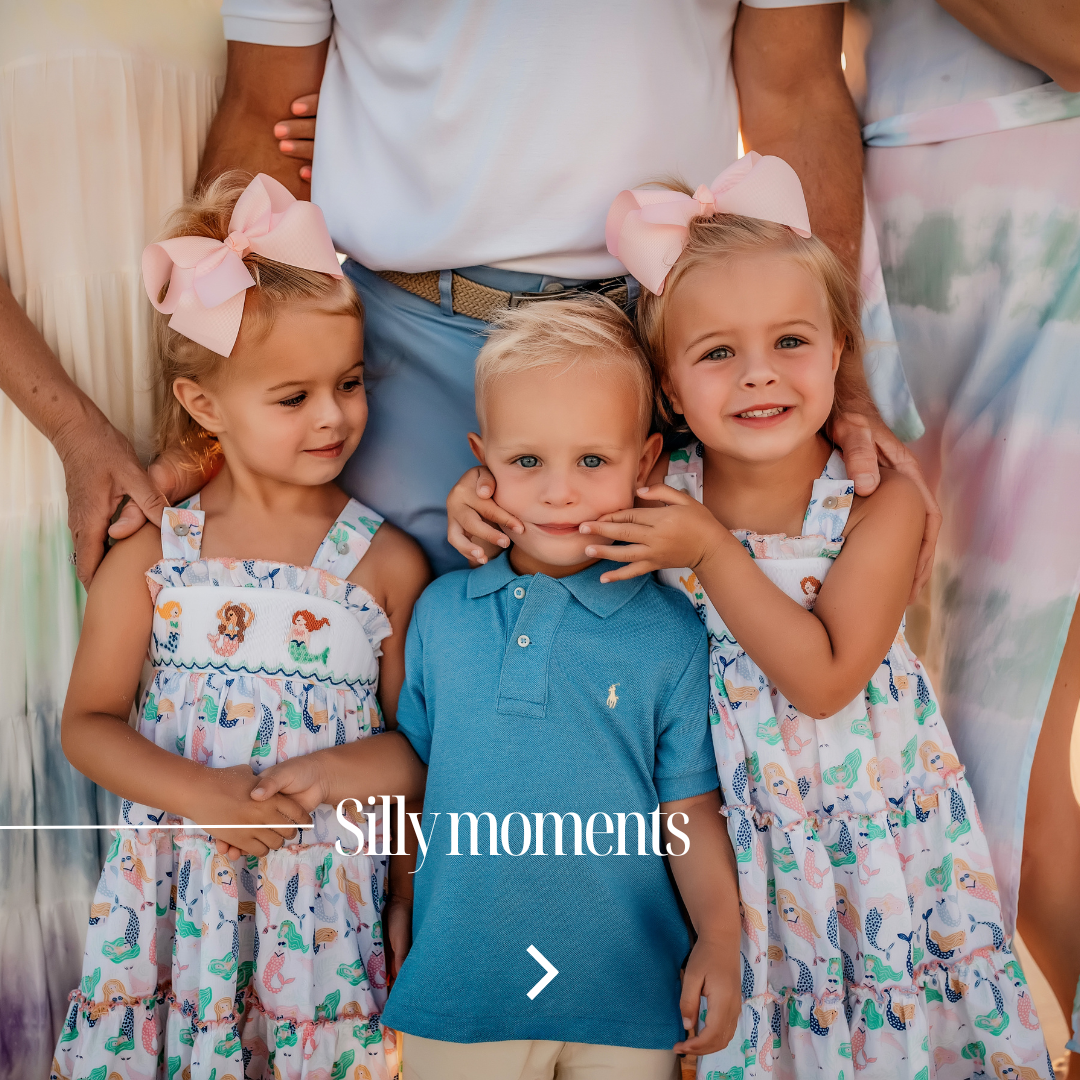Three young cousins in mermaid dresses and pink bows squishing their little cousin's cheeks during a silly candid moment at a 30A extended family beach session, photographed by Lisa Marie