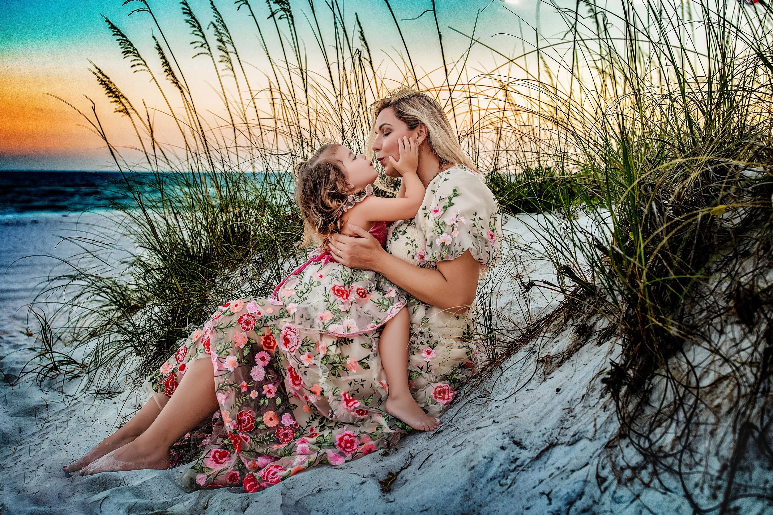 Maternity session of a mother and daughter sitting in the white sand at Dune Allen Beach.