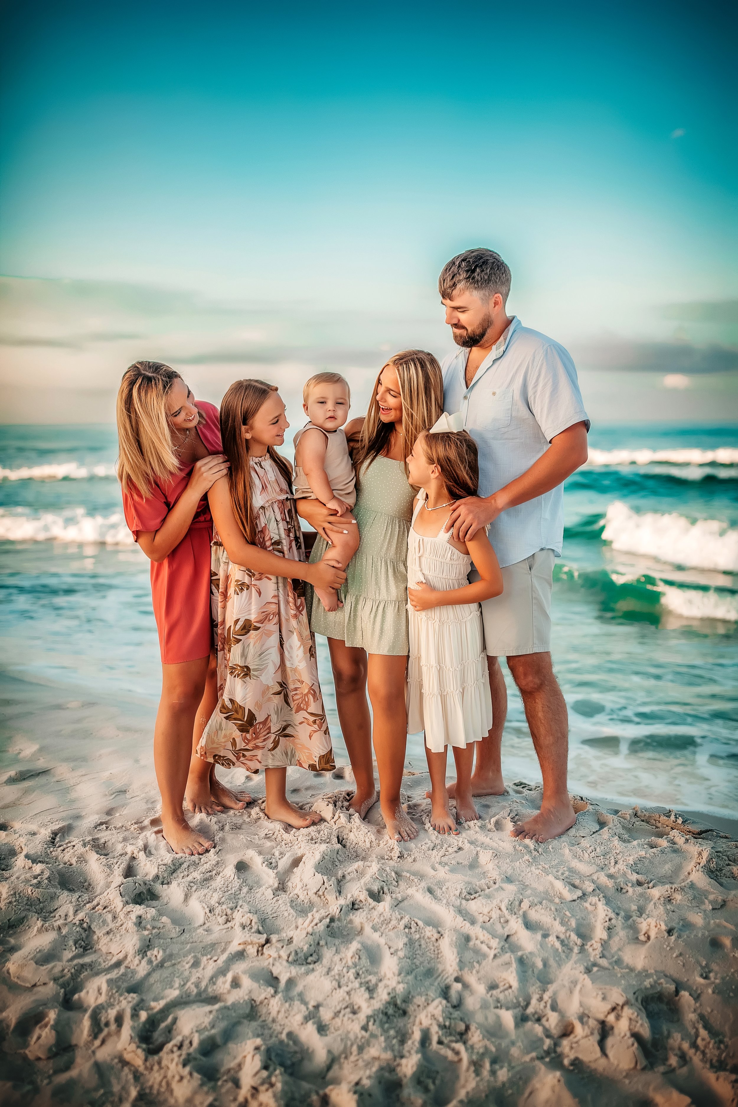 Family walking hand in hand along the shoreline at sunset during a relaxed 30A beach photography session.