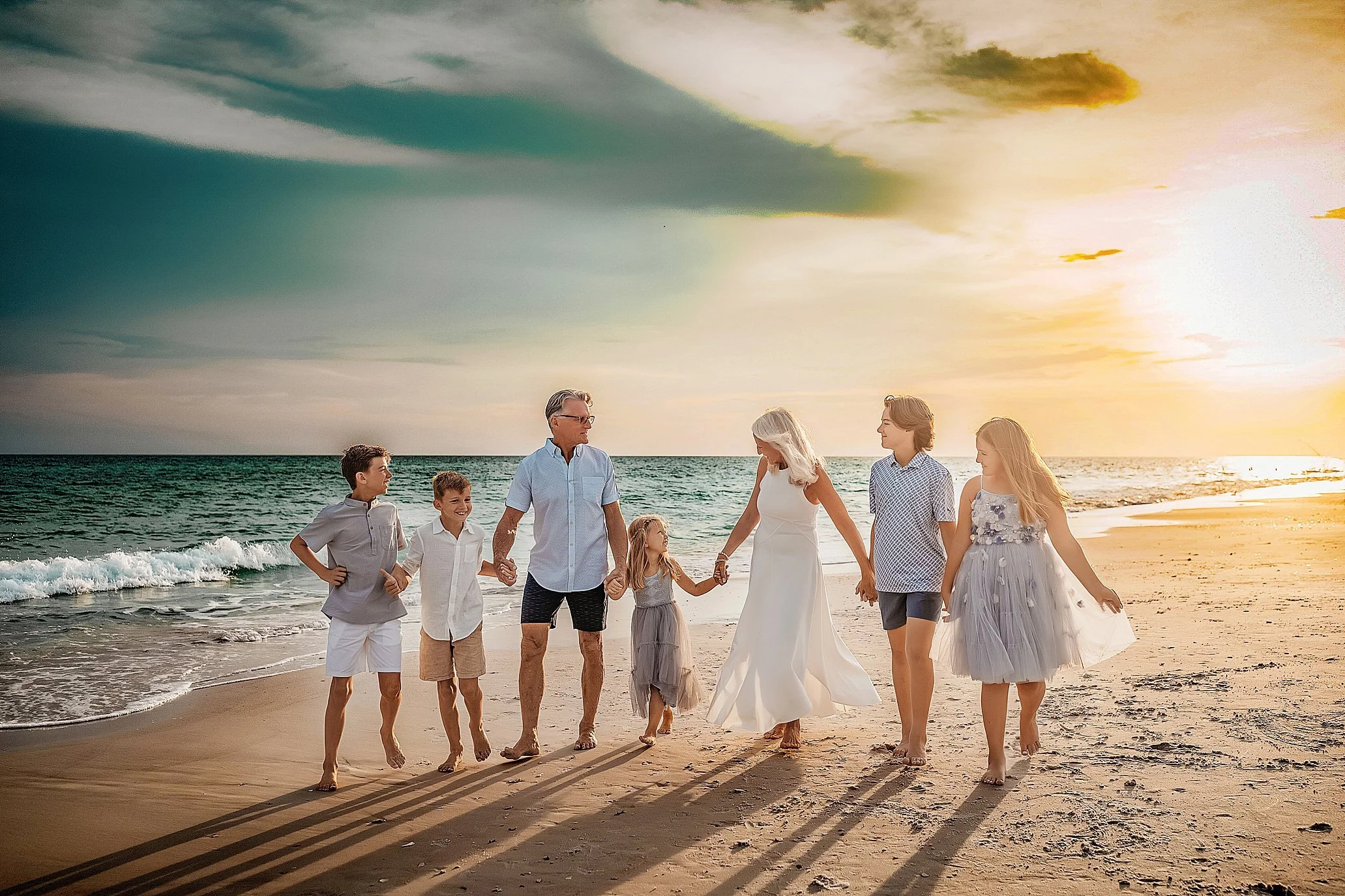 Grandparents with their grandchildren walking on the watercolor beach during their extended family beach session