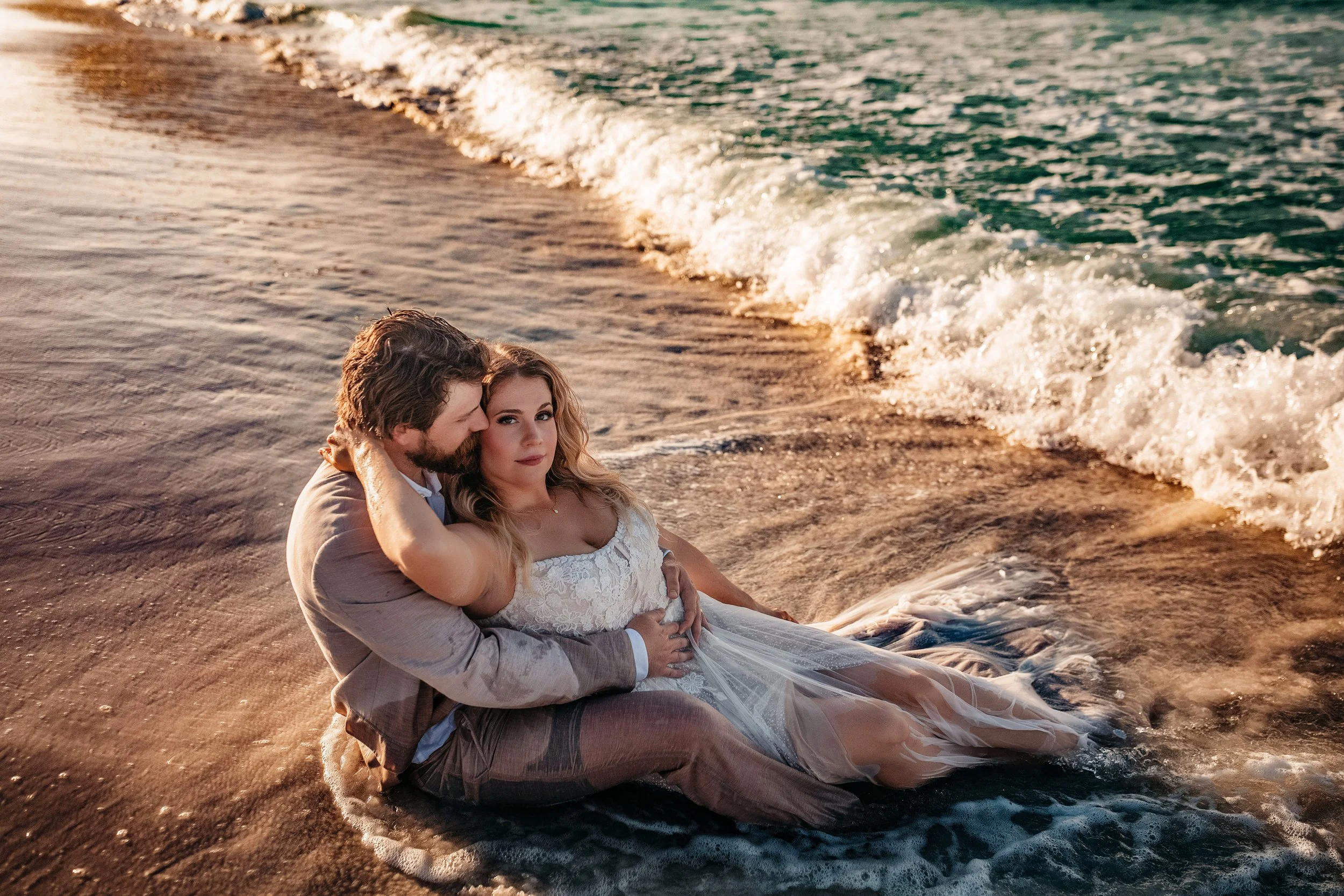 Playful sunrise beach wedding photo of bride and groom in the waves in Destin