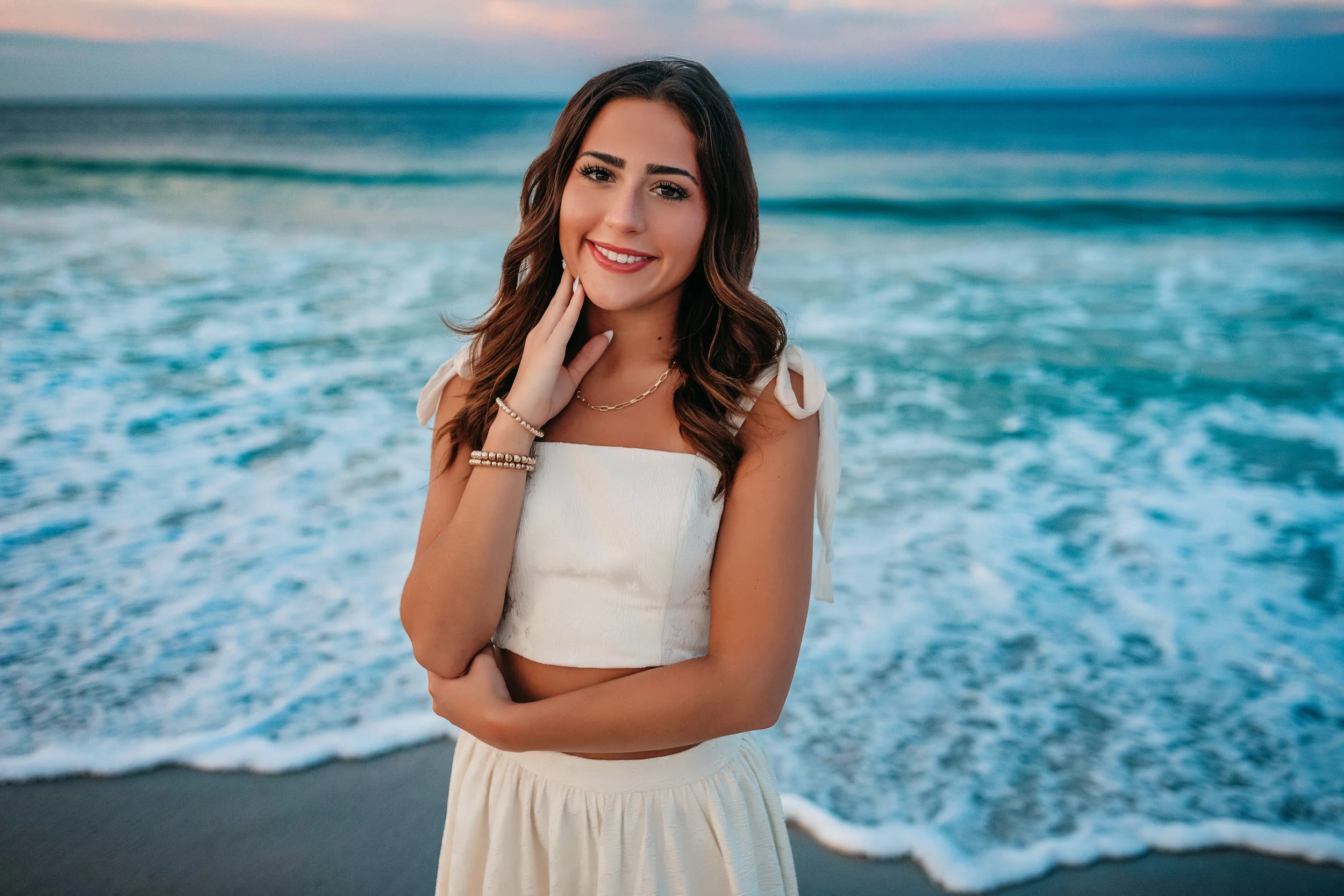 Close-up senior portrait at Panama City Beach with soft sunrise and calm waves.
