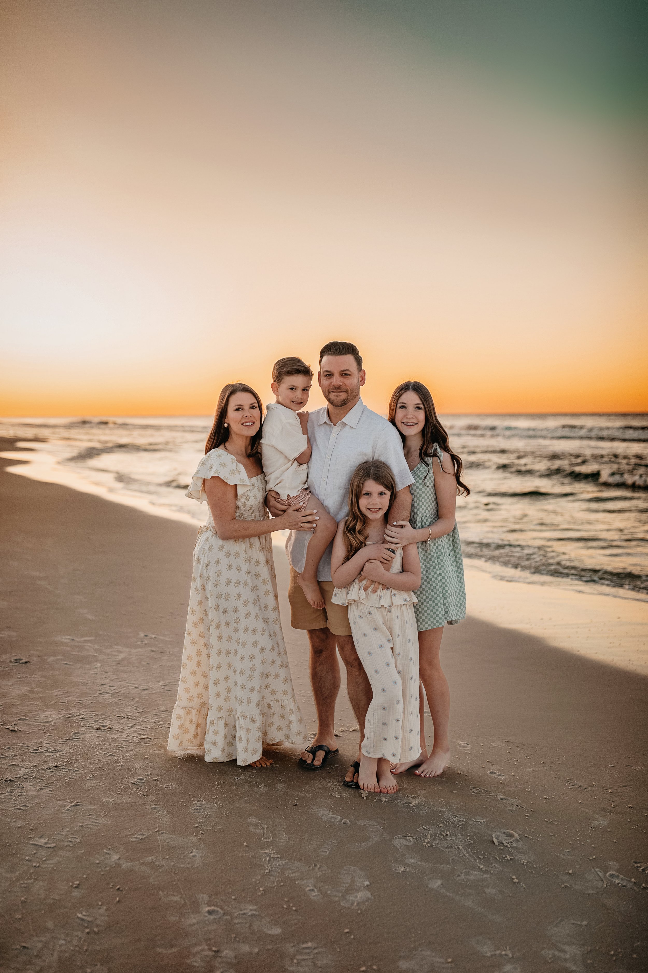 Candid editorial sunset portrait of a family of five on 30A coastal neutrals, natural movement, and warm light for luxury vacation sessions in WaterColor and Rosemary Beach.