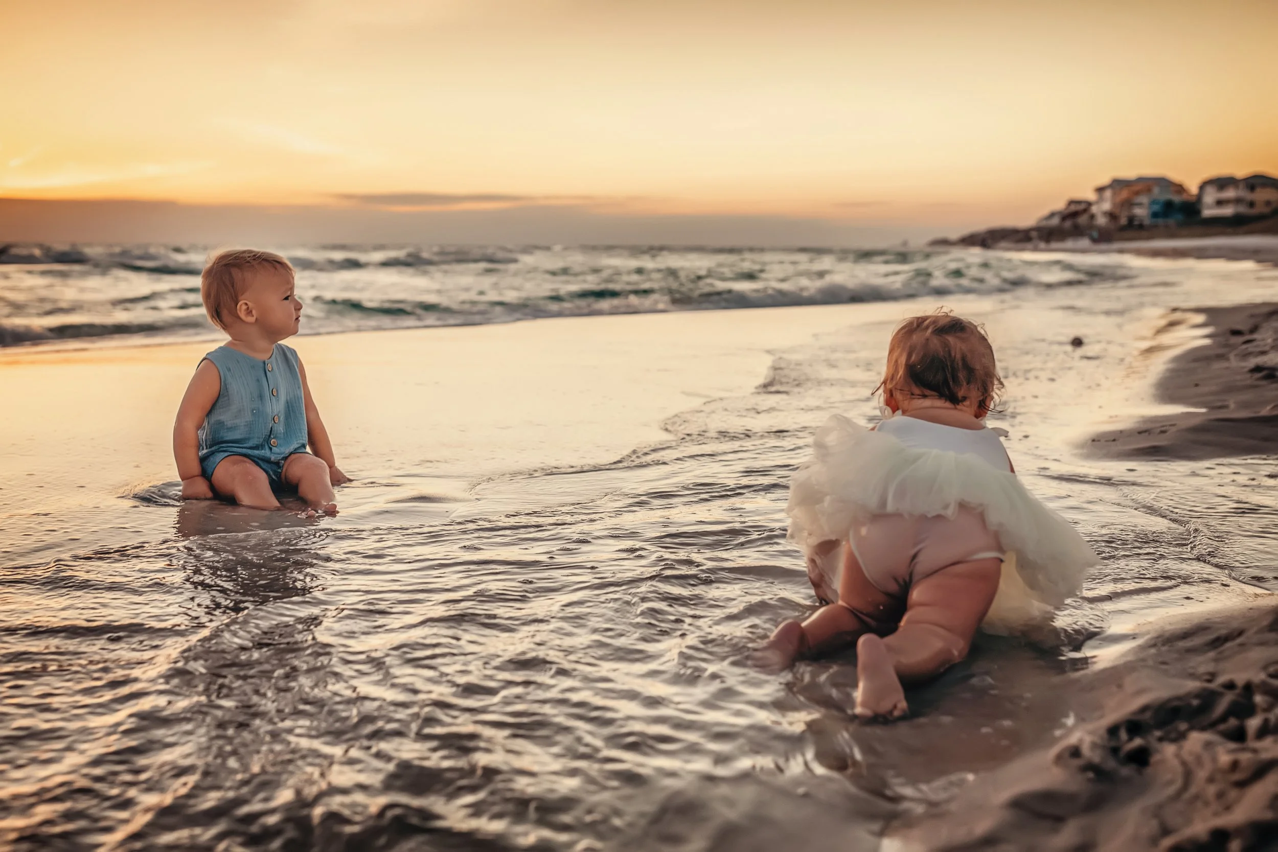 Two toddlers crawling in shallow water at sunset during a relaxed family photo session on 30A