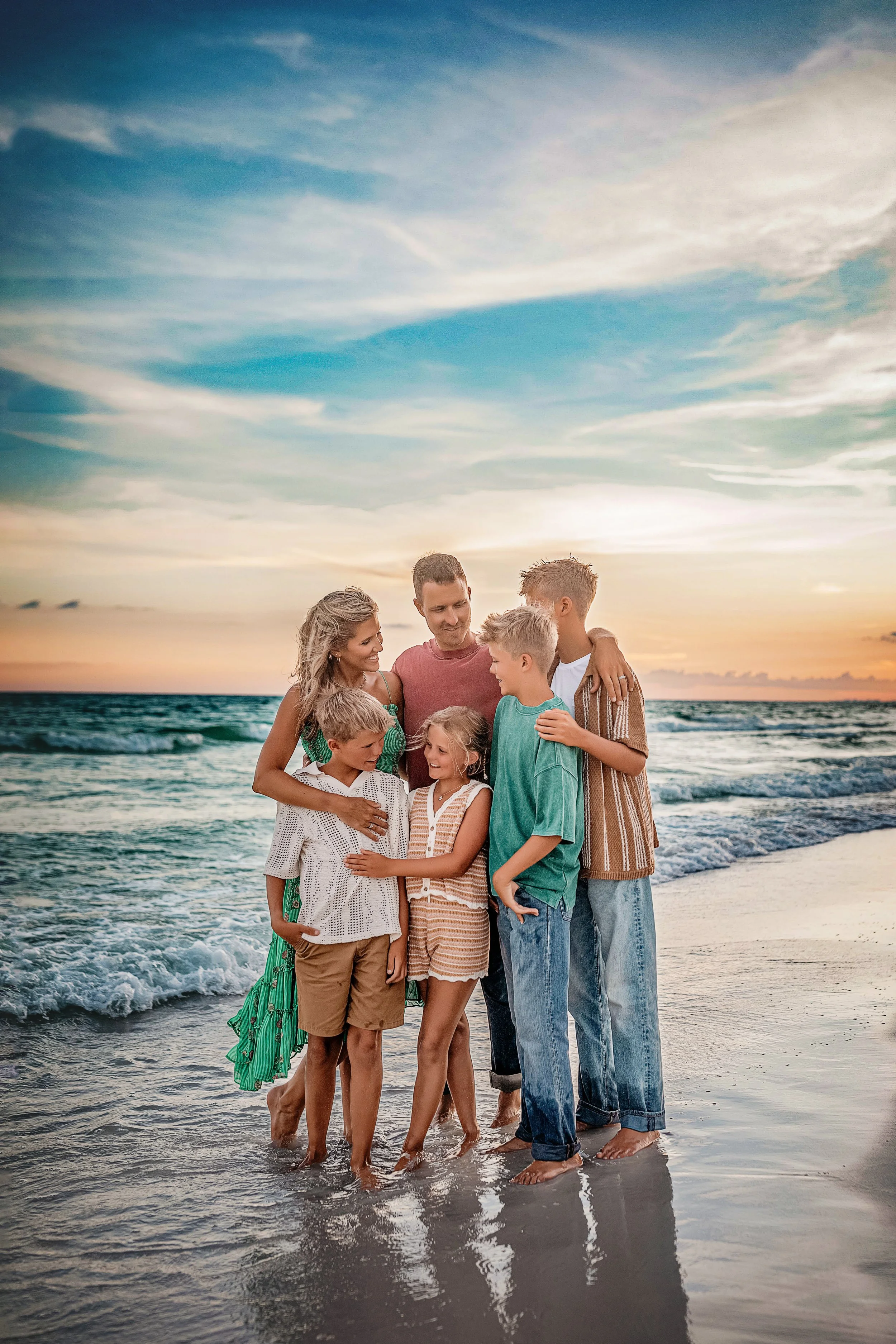 Family of six embracing along the Destin shoreline during sunset