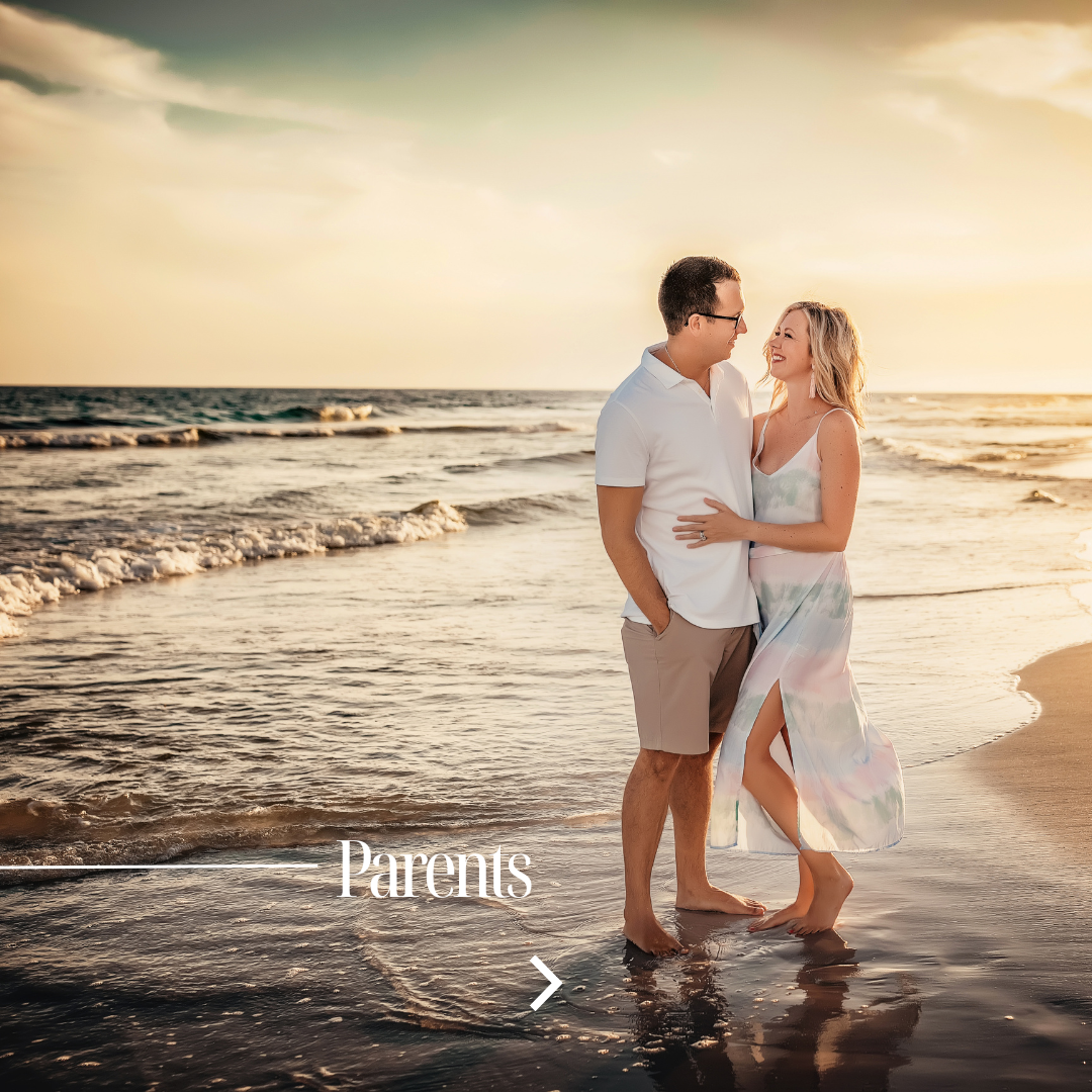 Couple embracing at the water's edge on the 30A Gulf Coast beach at golden hour sunset, parents couples portraits during extended family beach session by 30A photographer Lisa Marie