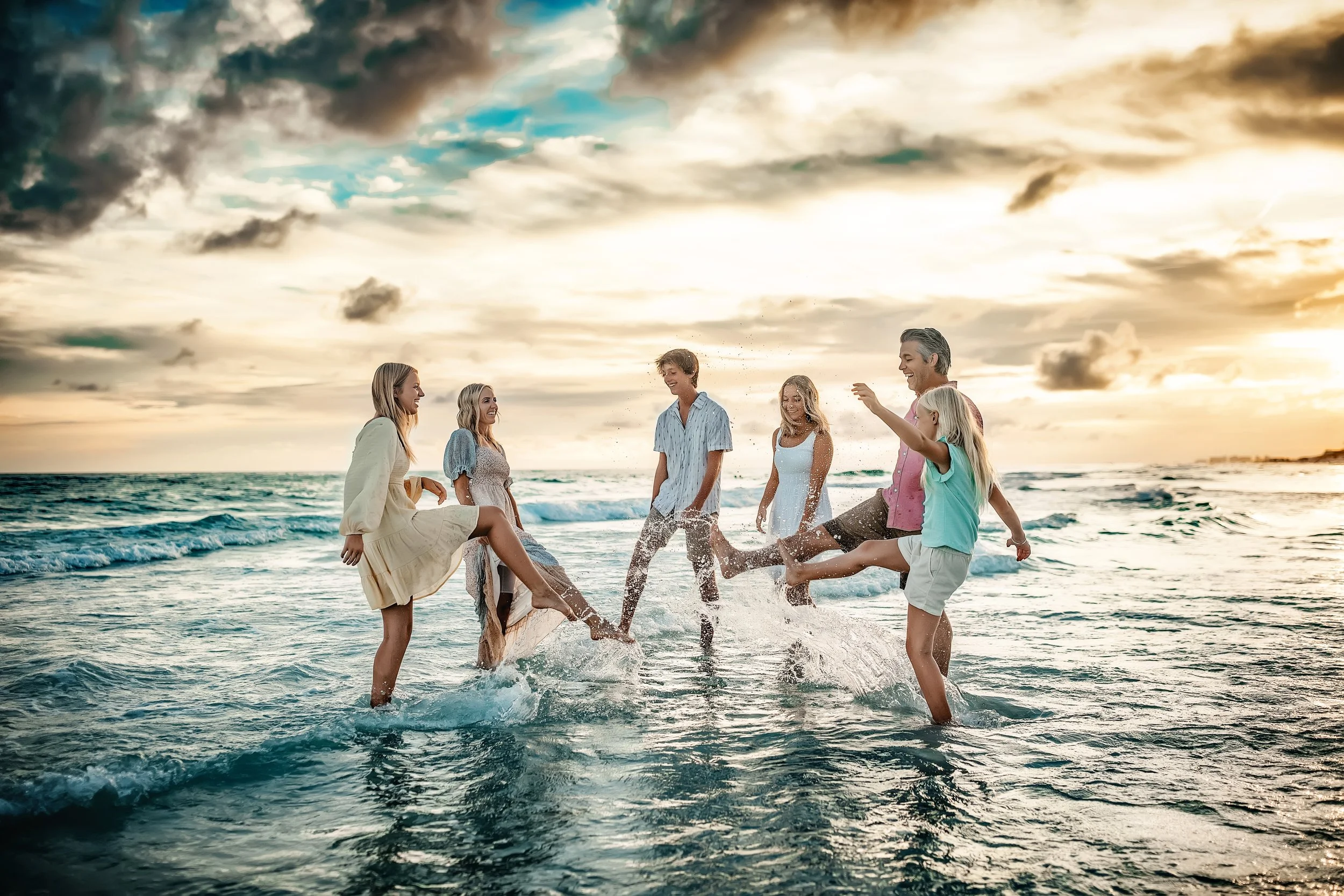 Family of six in the emerald water in Destin Florida splashing during their sunset session