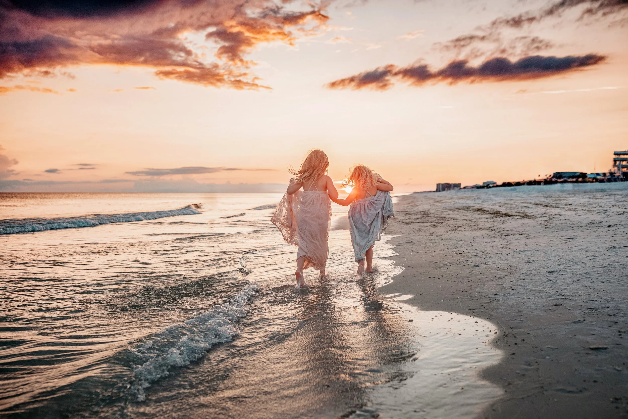 Two sisters walking along the water at sunset during an Inlet Beach family photography session on 30A