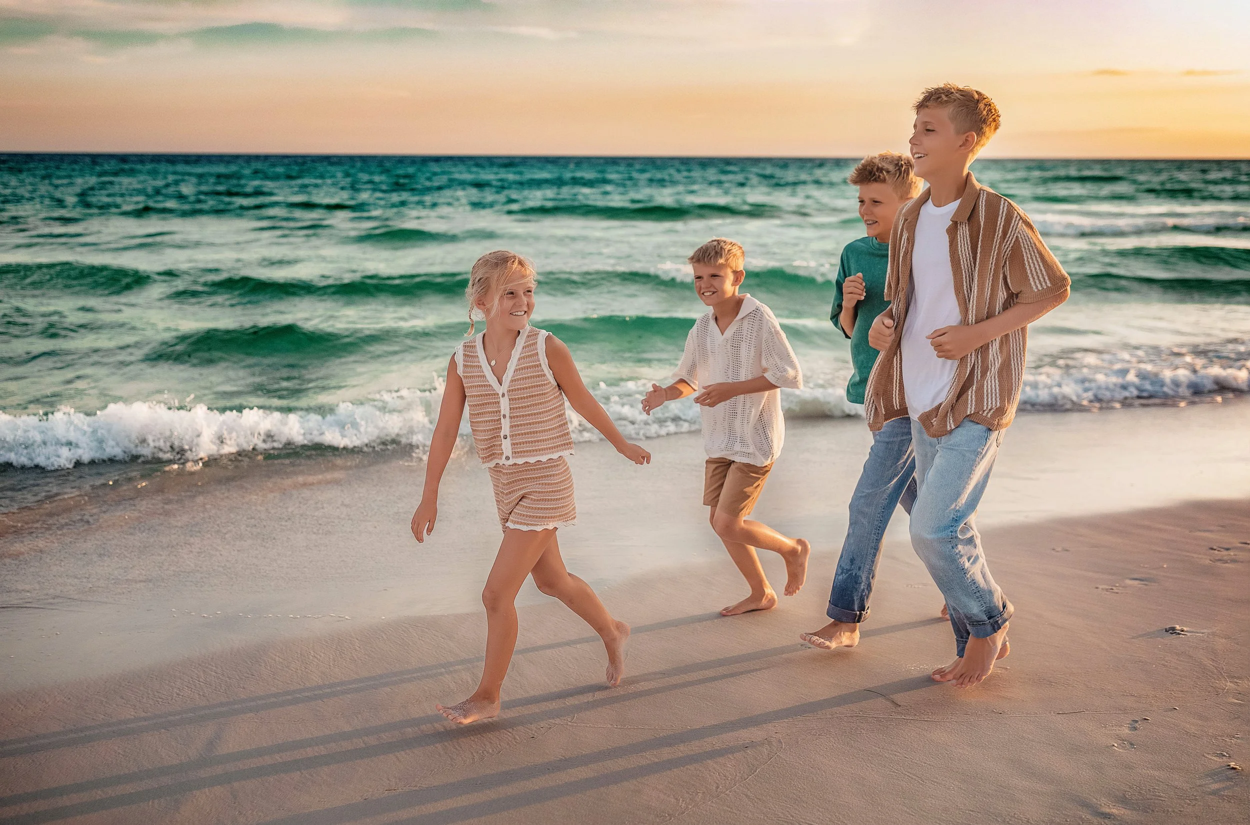 Four kids running on Destin Florida beach at sunset in coordinated tan neutral outfits — 30A beach photographer