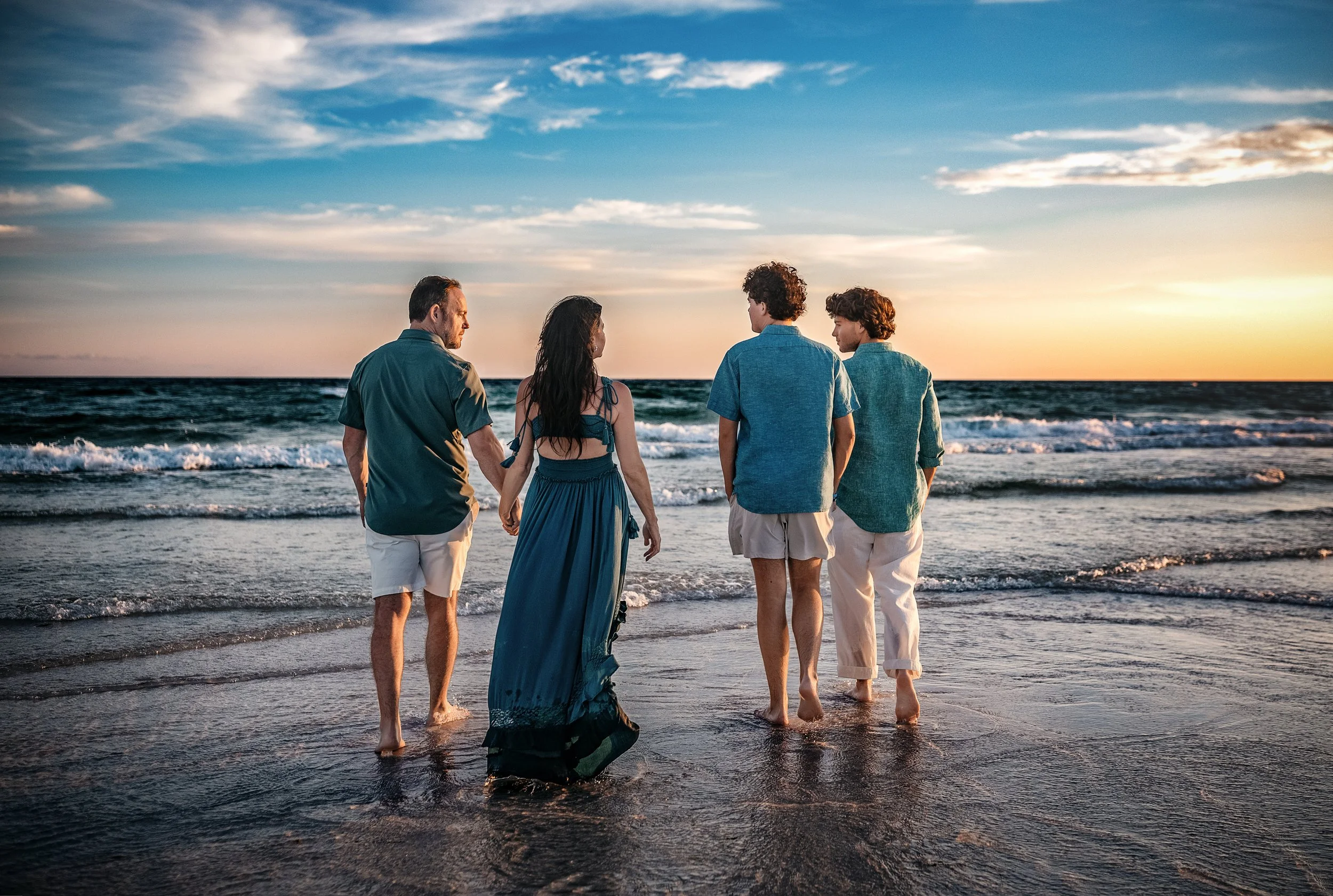 A mother and father looking out to the destin emerald water with their two teenage sons