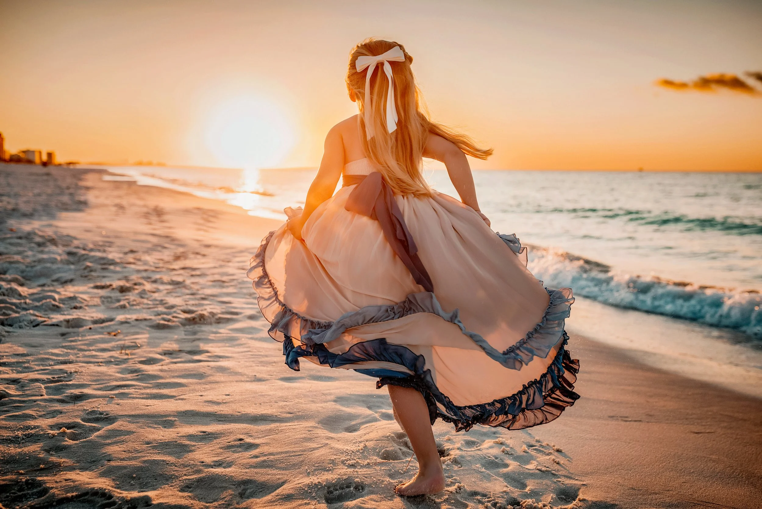 Little girl in a flowy dress running on the Destin beach towards the sunrise at her family beach session
