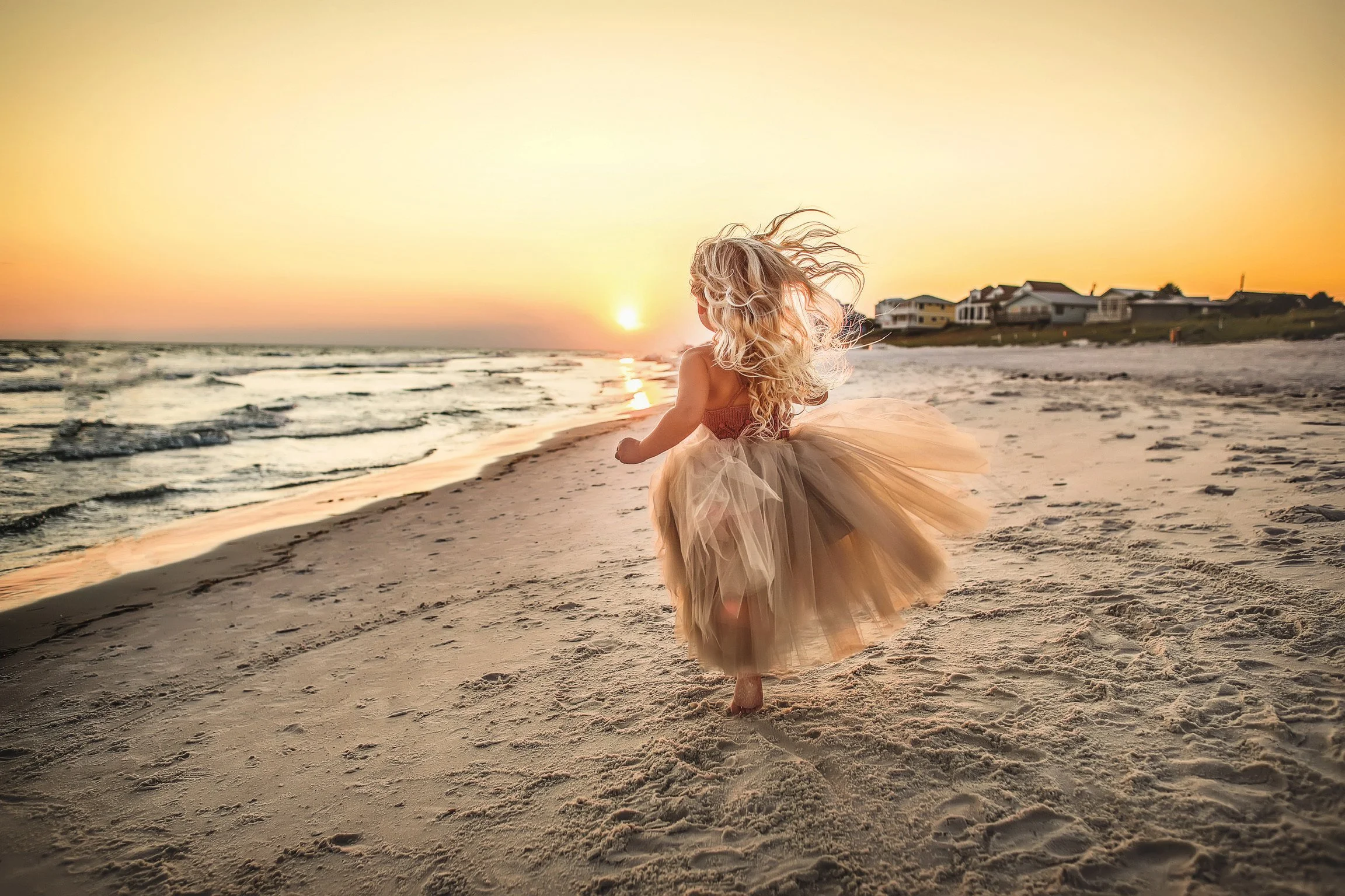 Child in tulle dress running towards the sunset on the Destin beaches