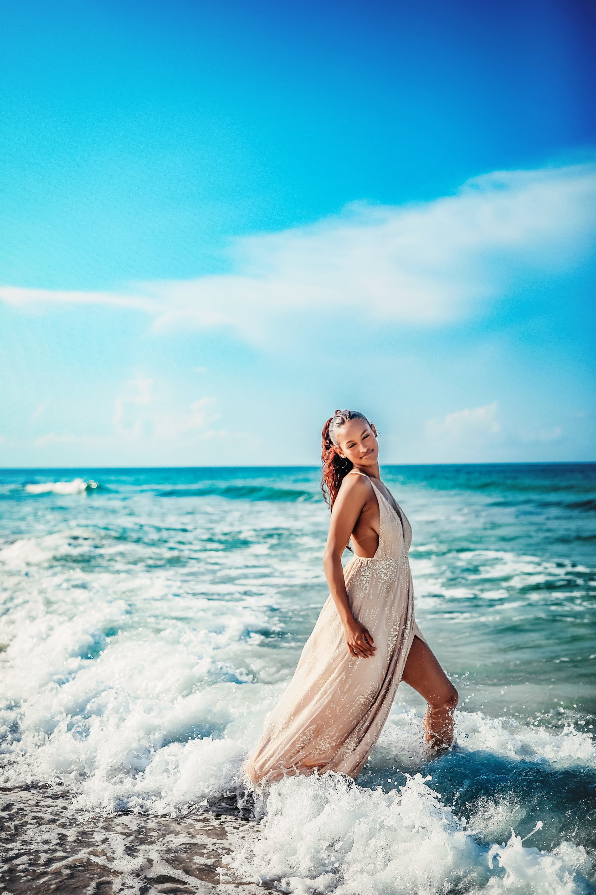 A high school senior girl standing in the waves during her  luxurious senior beach session