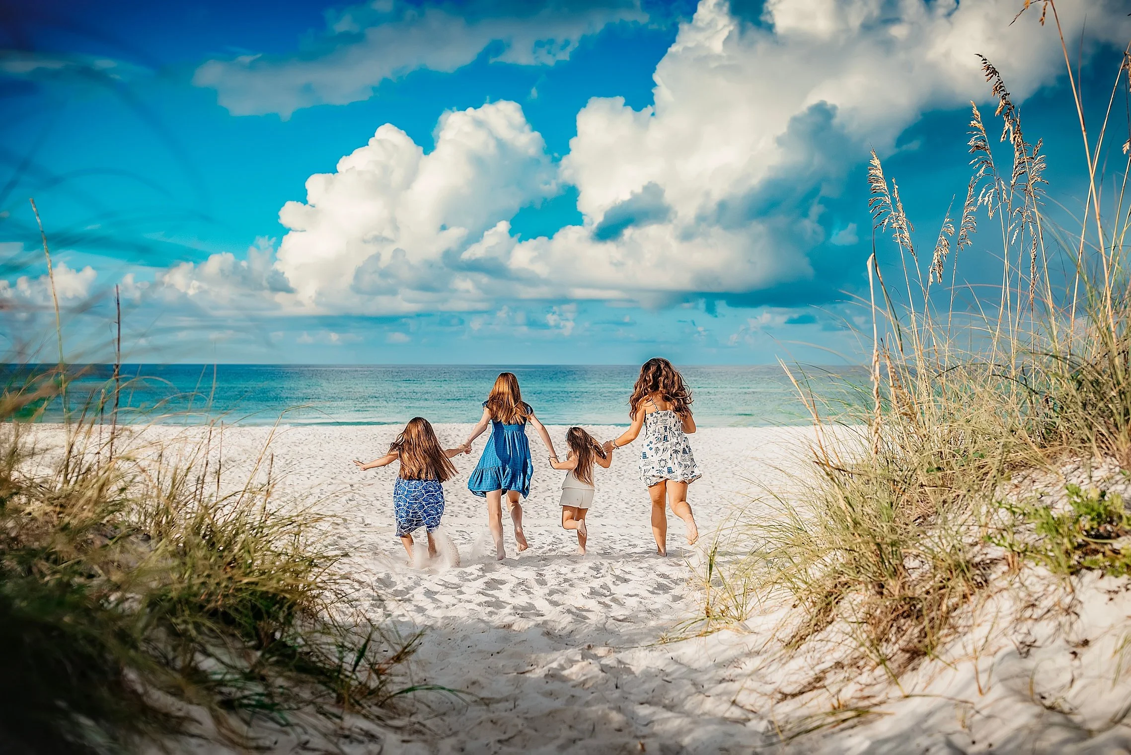 Young children running and playing in the sand at Miramar Beach during a sunset session.