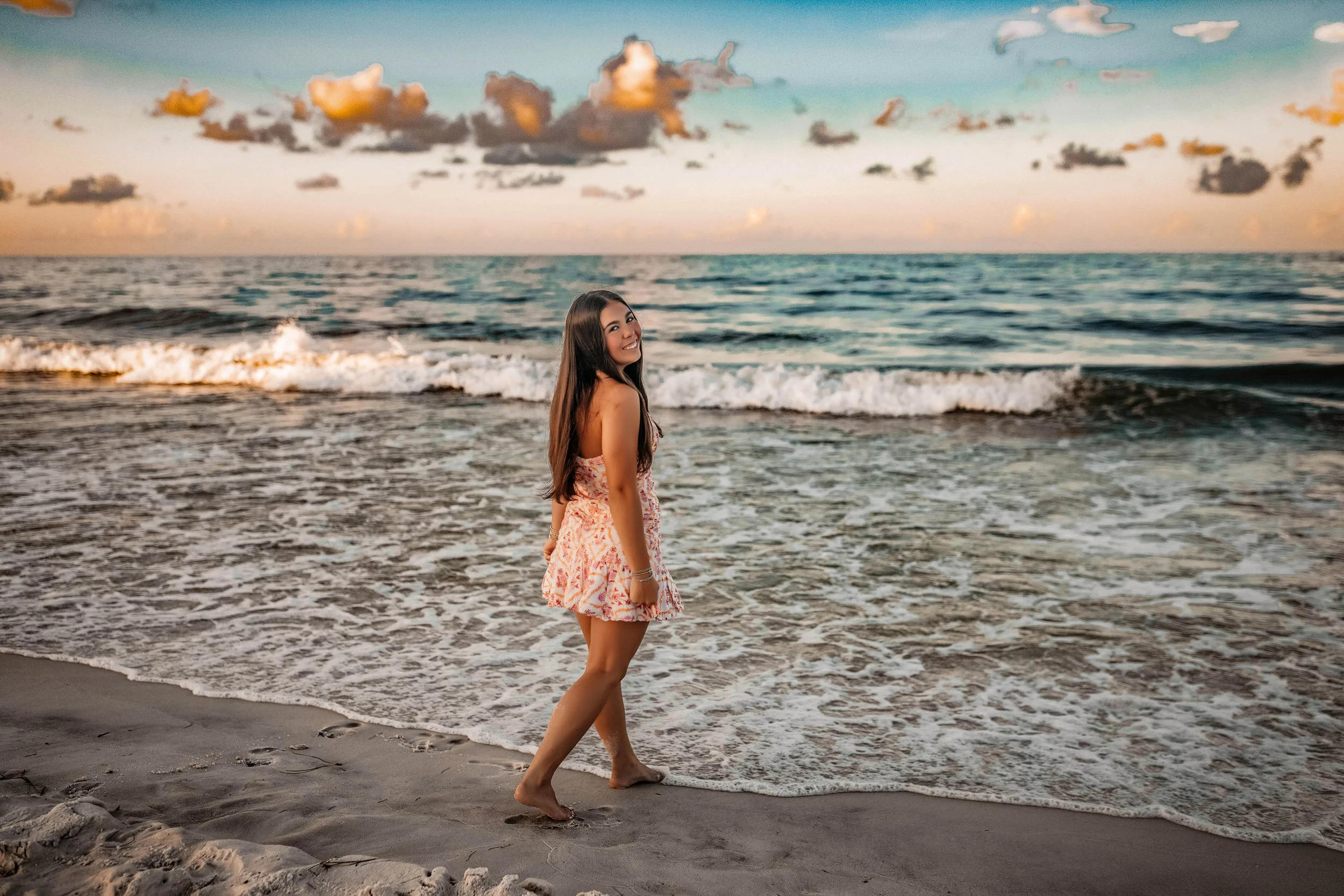 Highschool senior girl walking into the emerald water in Seaside Florida during her beach session