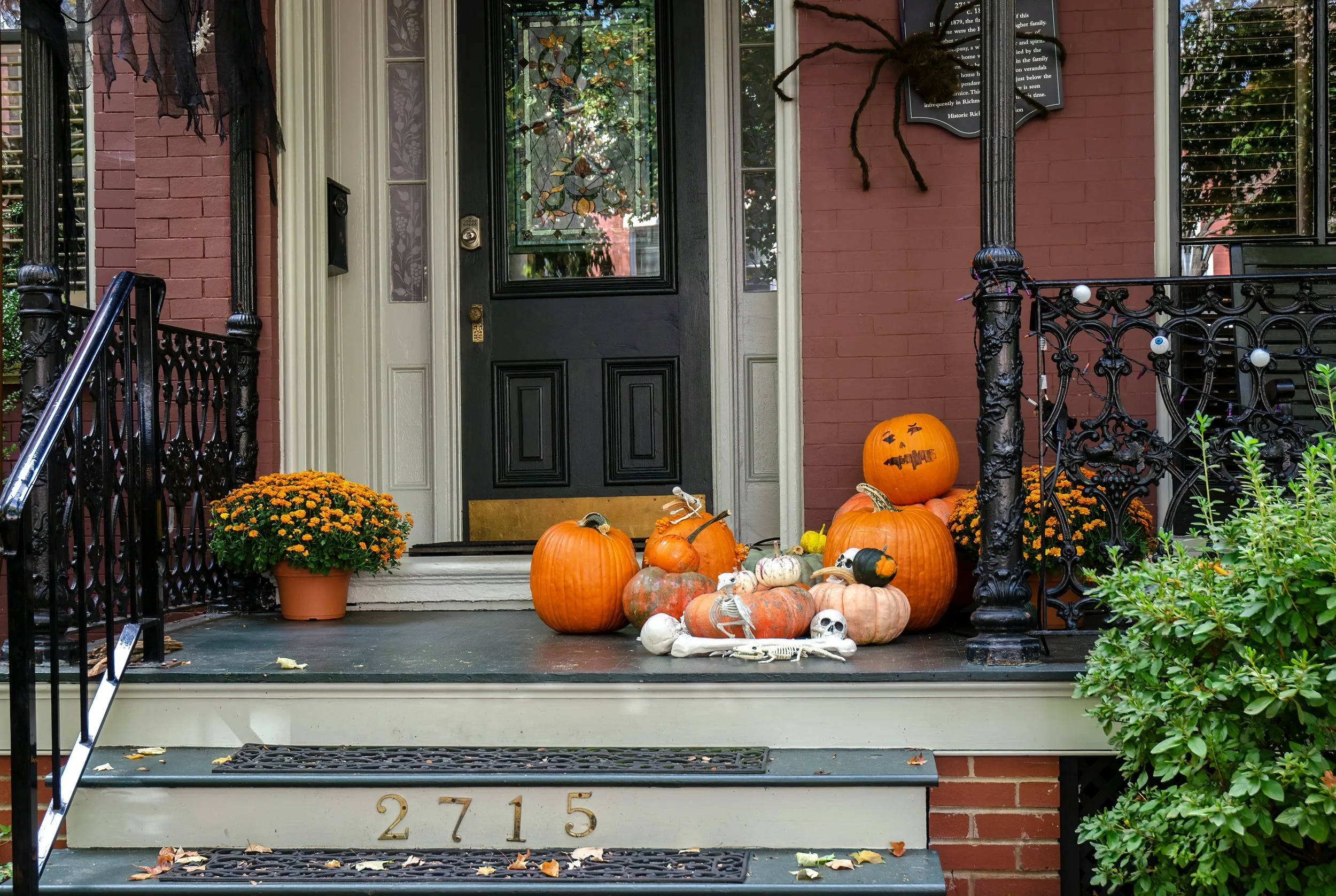 Front porch with pumpkins, mums and halloween decorations like a large spider on the wall