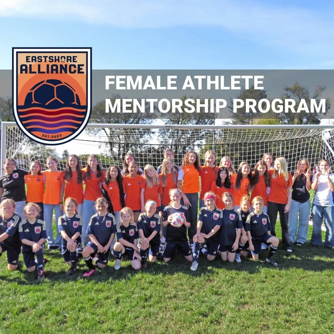 Eastshore Alliance FC girls soccer players pose together in front of a goal during a Female Athlete Mentorship Program event, highlighting community, mentorship, and female athlete empowerment.