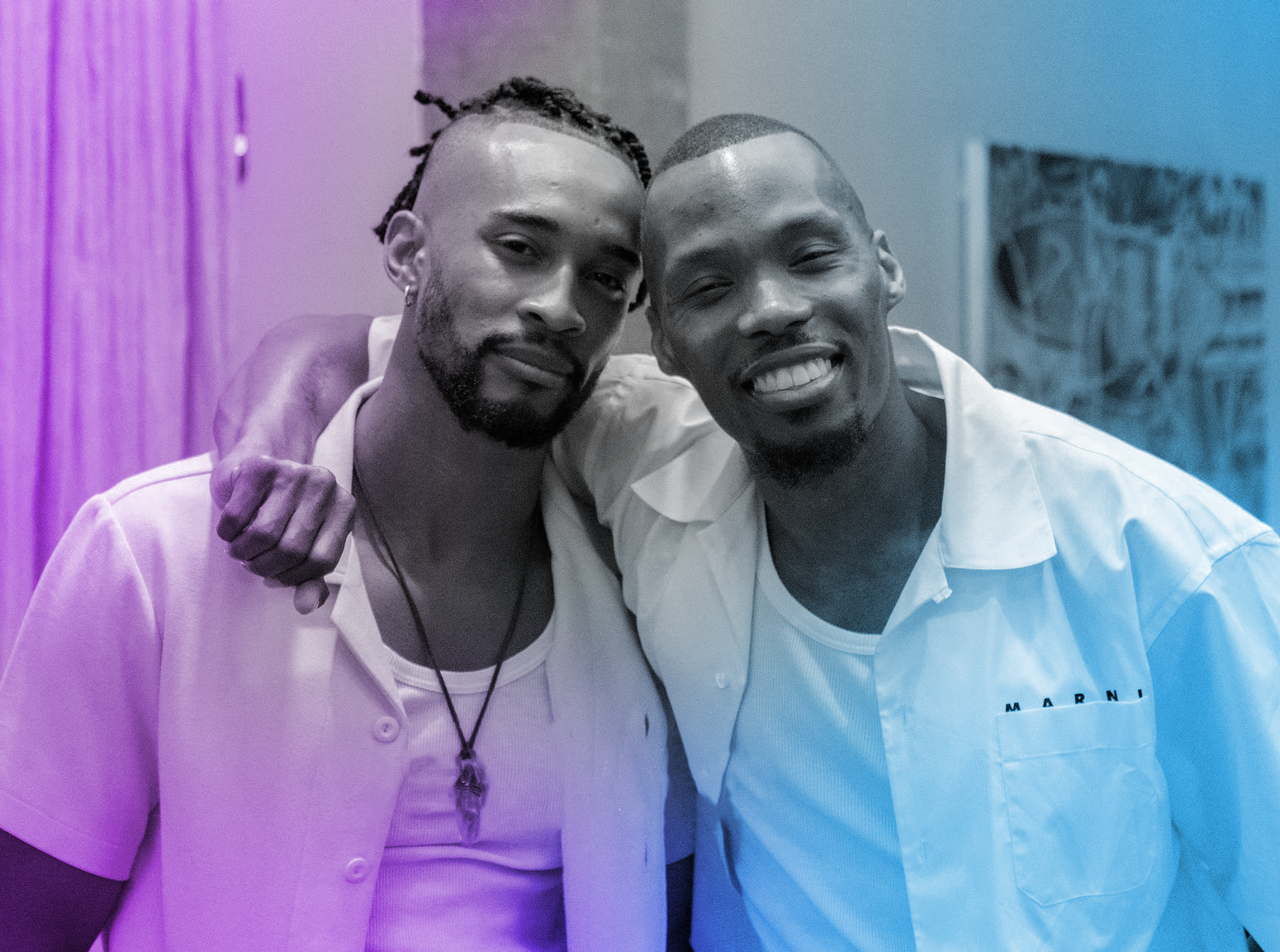 A portrait of the cofounders of Deviant Society, Micah Roseboro and Montell F. Stansberry. They're both handsome black men, smiling at the viewer, and Montell has his arm wrapped around Micah's shoulders.