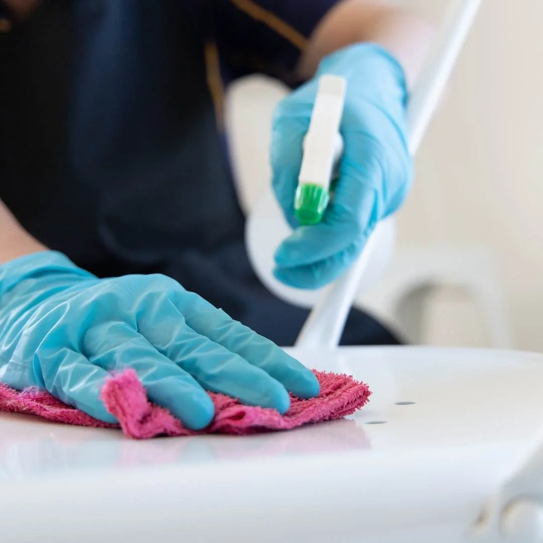Grooming worker wearing blue gloves cleaning a white surface with a pink cloth
