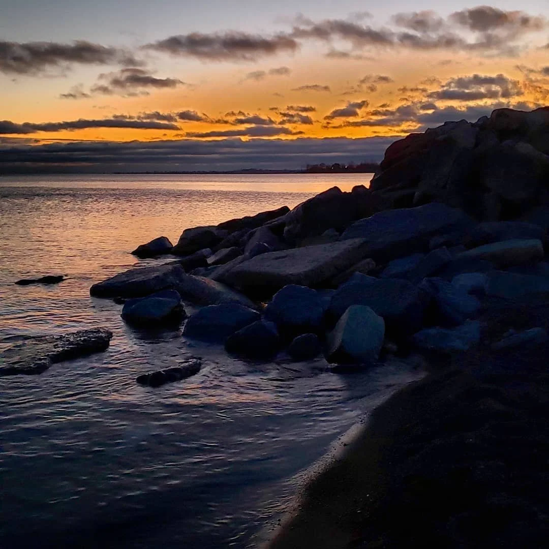 View of The Beach, Toronto at sunset, looking over a rocky outcrop to Lake Ontario