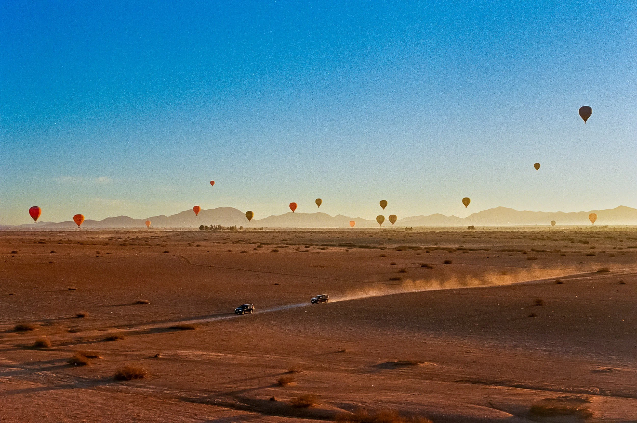Hot-air balloons floating above the Agafay Desert near Marrakech at sunrise.