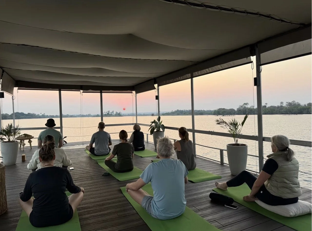 Small retreat group practising sunrise yoga overlooking the Zambezi River at Victoria Falls