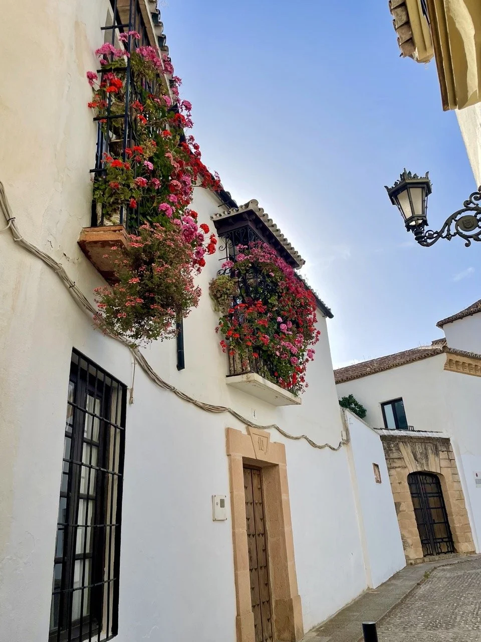 Charming Andalusian street with whitewashed houses and flower-filled balconies, part of the cultural flavor of our walking retreat in Spain.