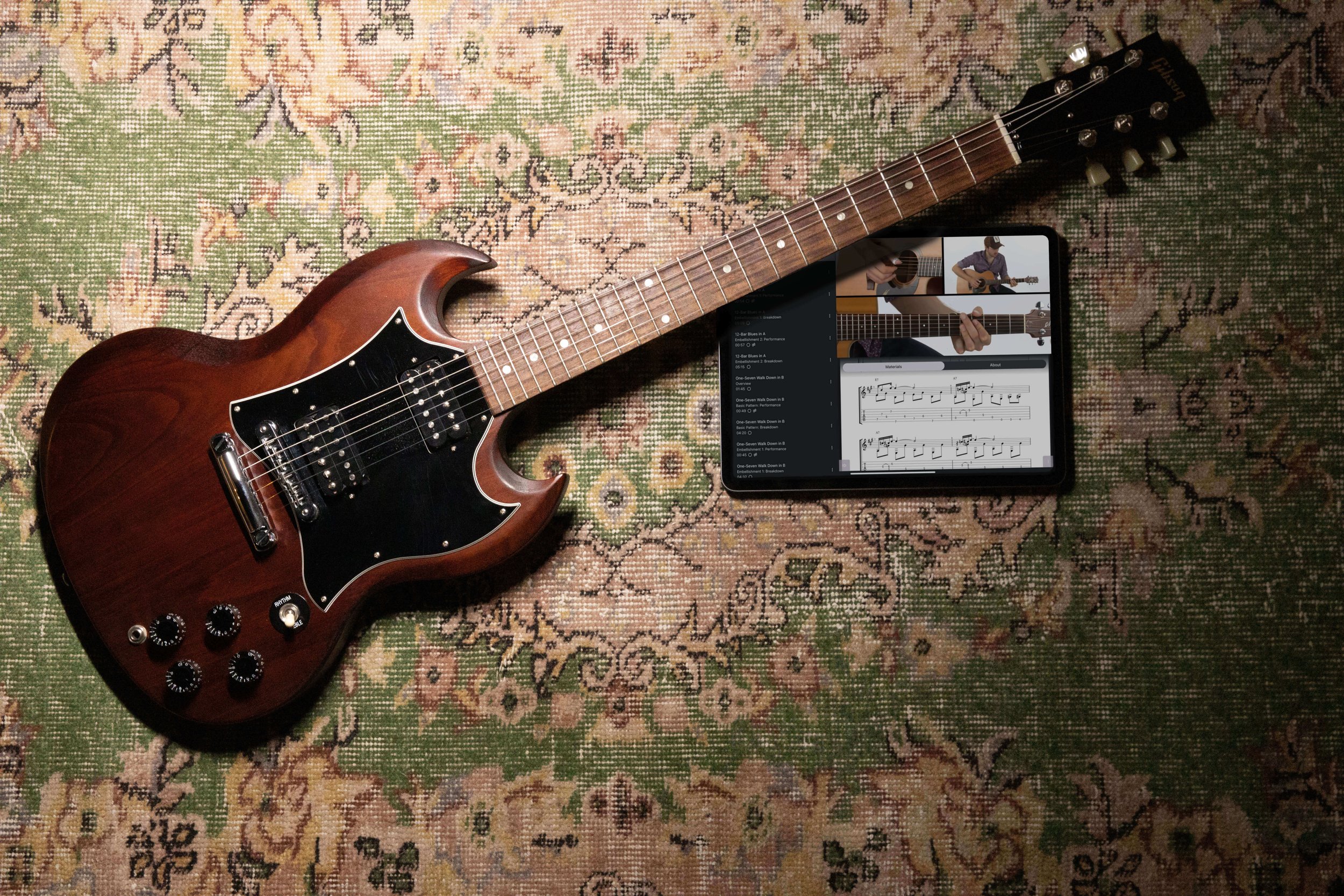 Photograph of a guitar and an iPad featuring a screen from the TrueFire iOS app.