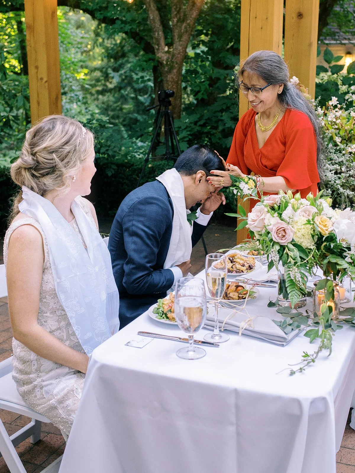 Groom bows his head as his mother places her hands on him during a traditional blessing