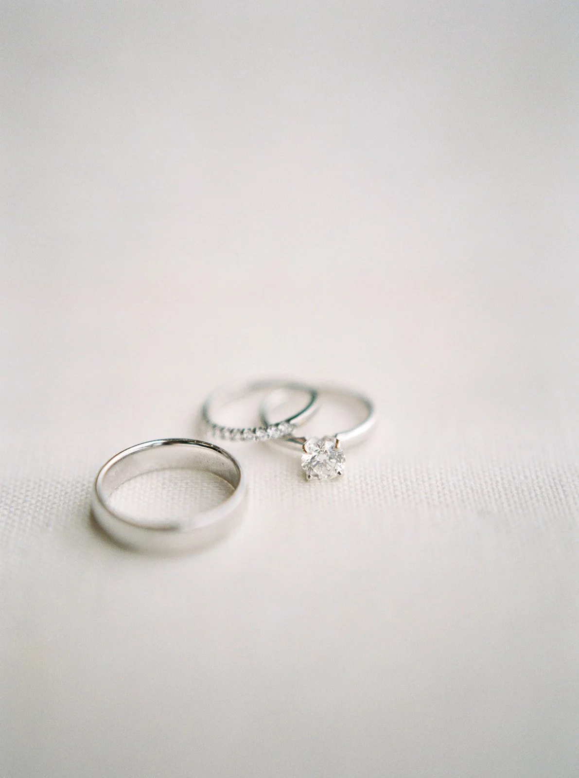 Three wedding rings arranged on soft white fabric during an intimate Oregon wedding.