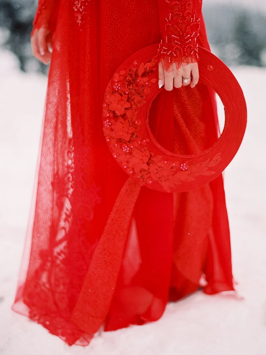 Bride holding red khăn đóng, showing intricate beadwork and lace detail of áo dài.