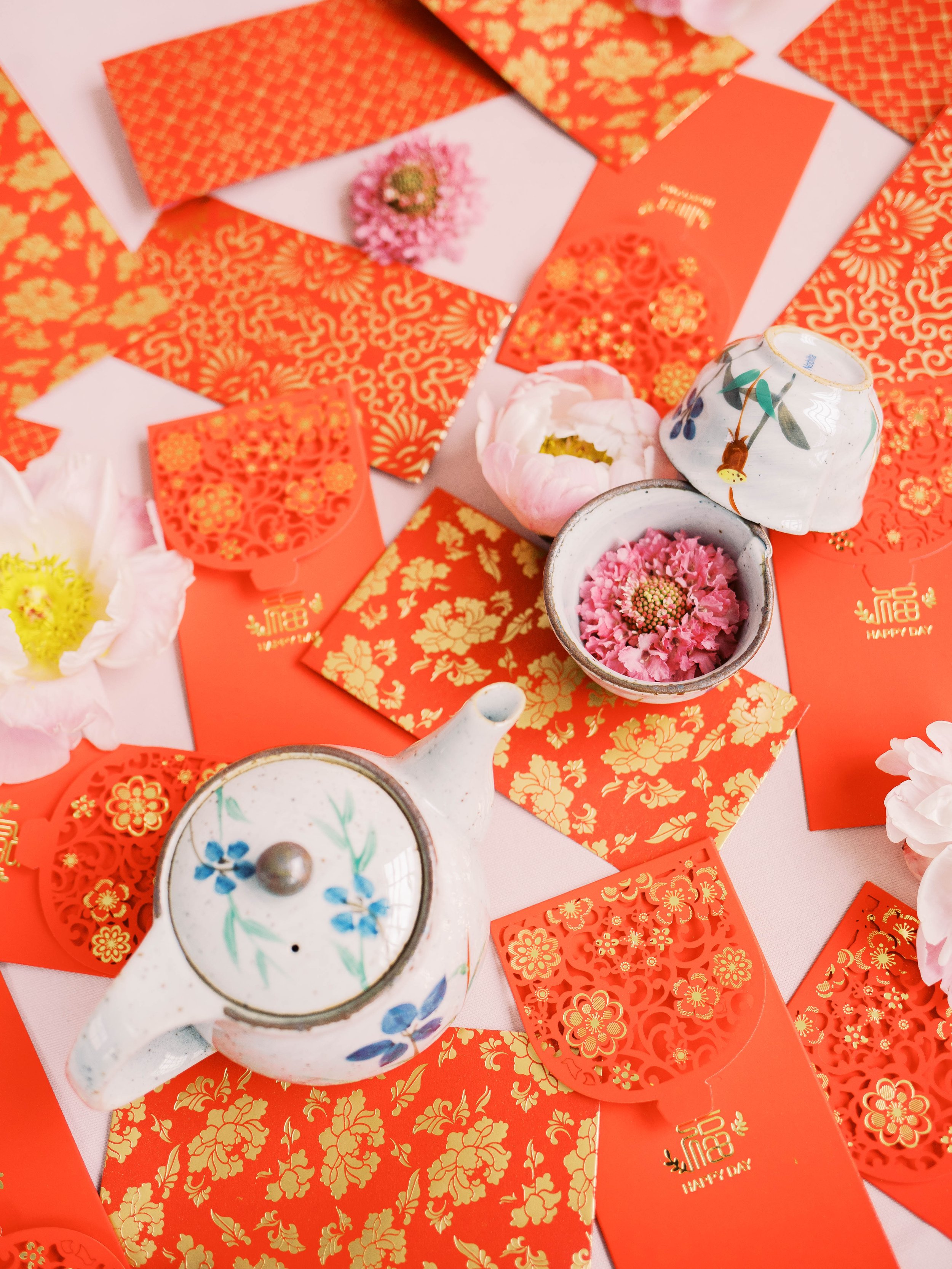 Chinese tea set, red envelopes and pink flowers arranged for a modern tea ceremony.
