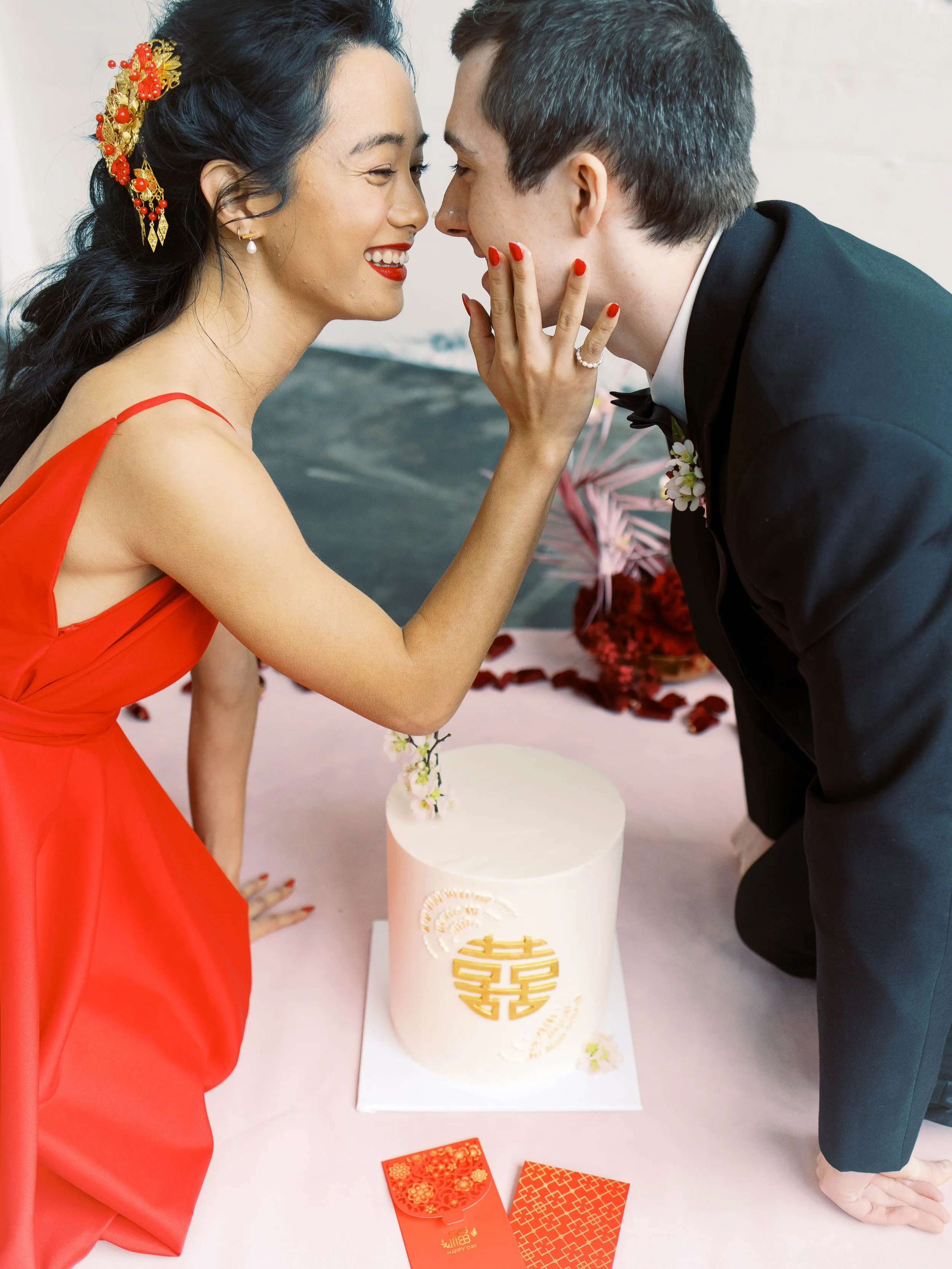 Couple leans toward each other beside a wedding cake during a modern Chinese tea ceremony.