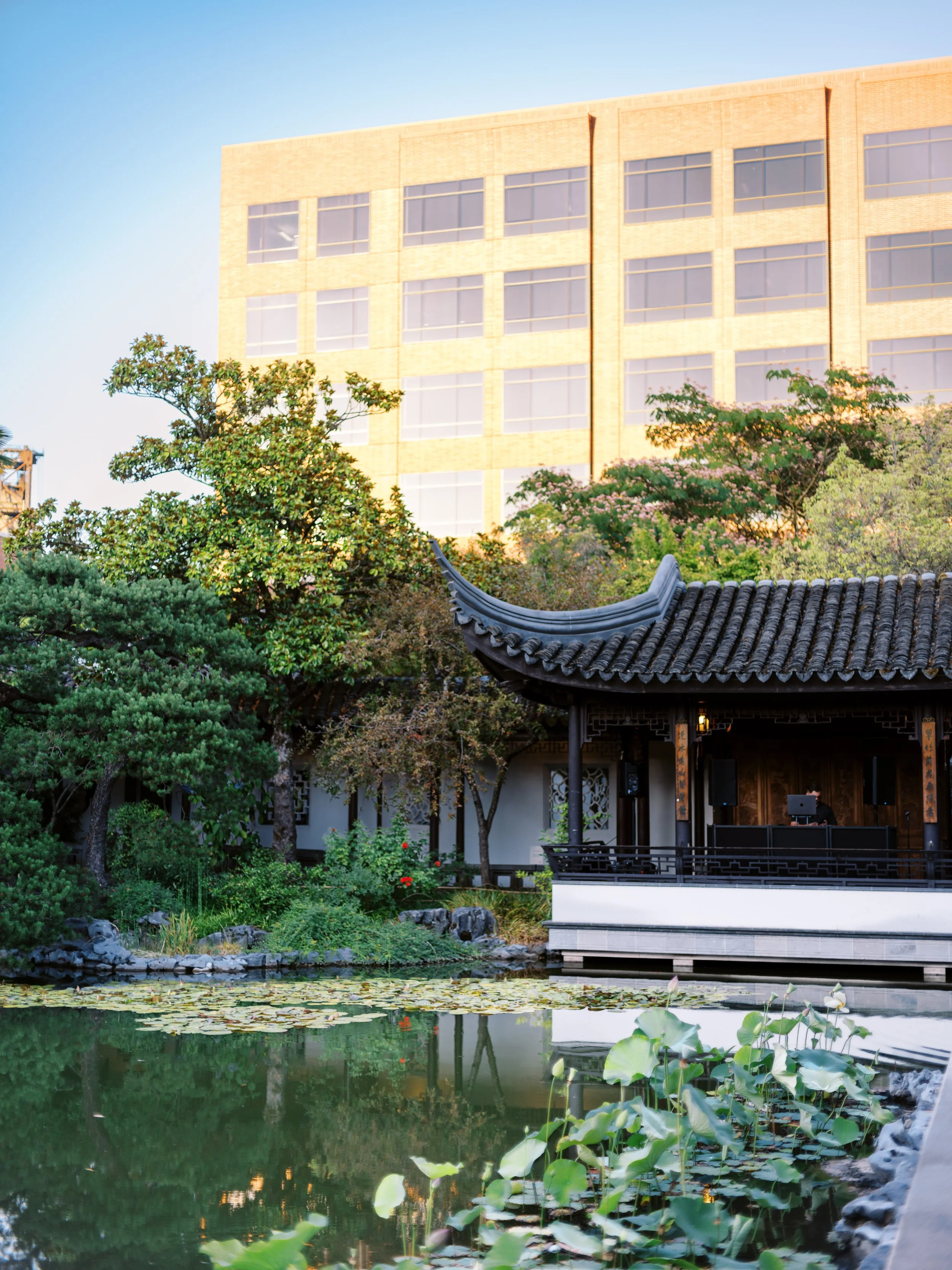 Wide view of Lan Su Chinese Garden wedding reception area with pavilion, koi pond, and surrounding greenery in Portland.