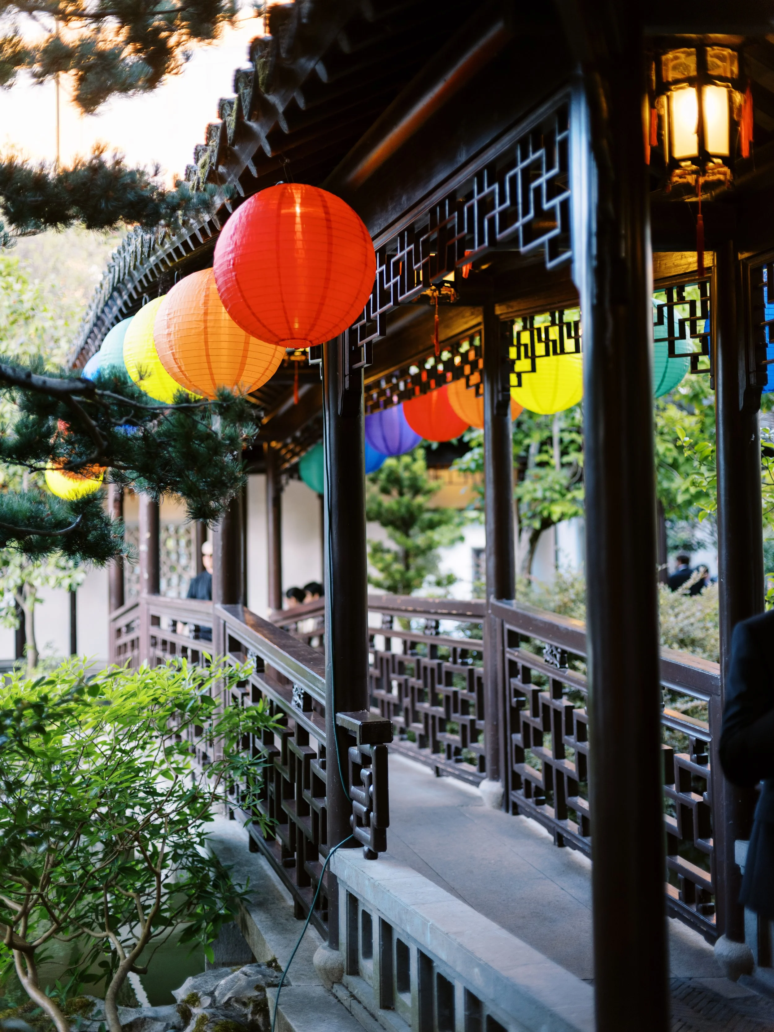Colorful lanterns hanging along a covered walkway at Lan Su Chinese Garden during an evening wedding celebration