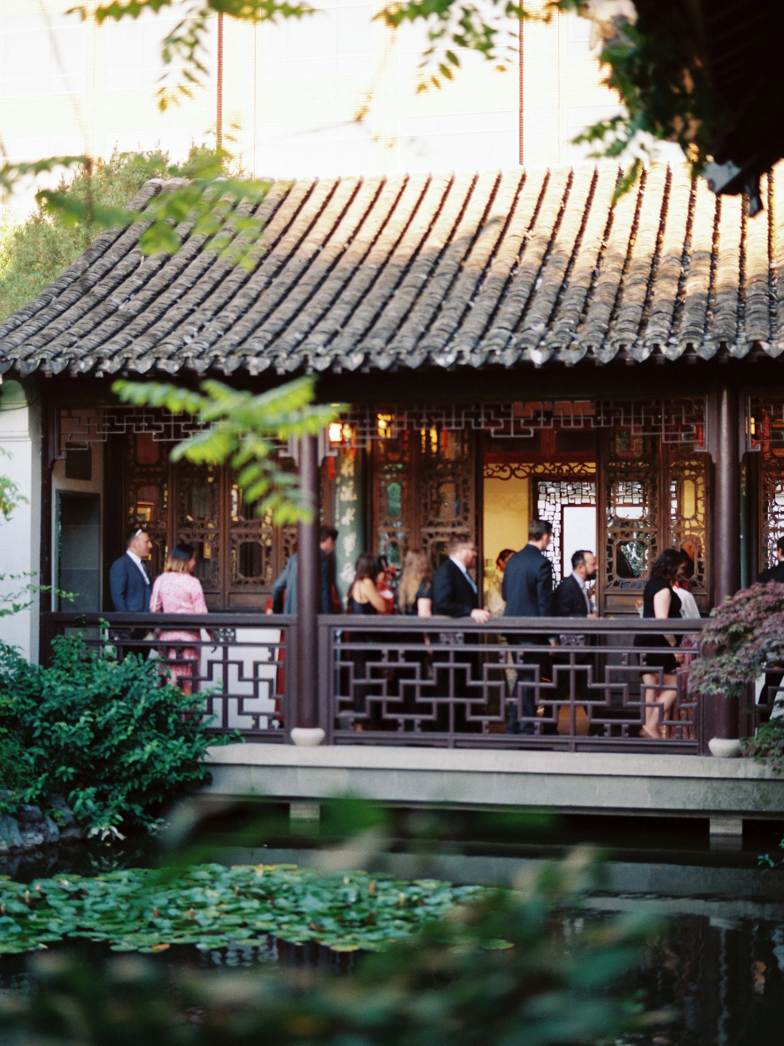 Wedding guests walking through a covered pavilion at Lan Su Chinese Garden in Portland during an intimate reception.